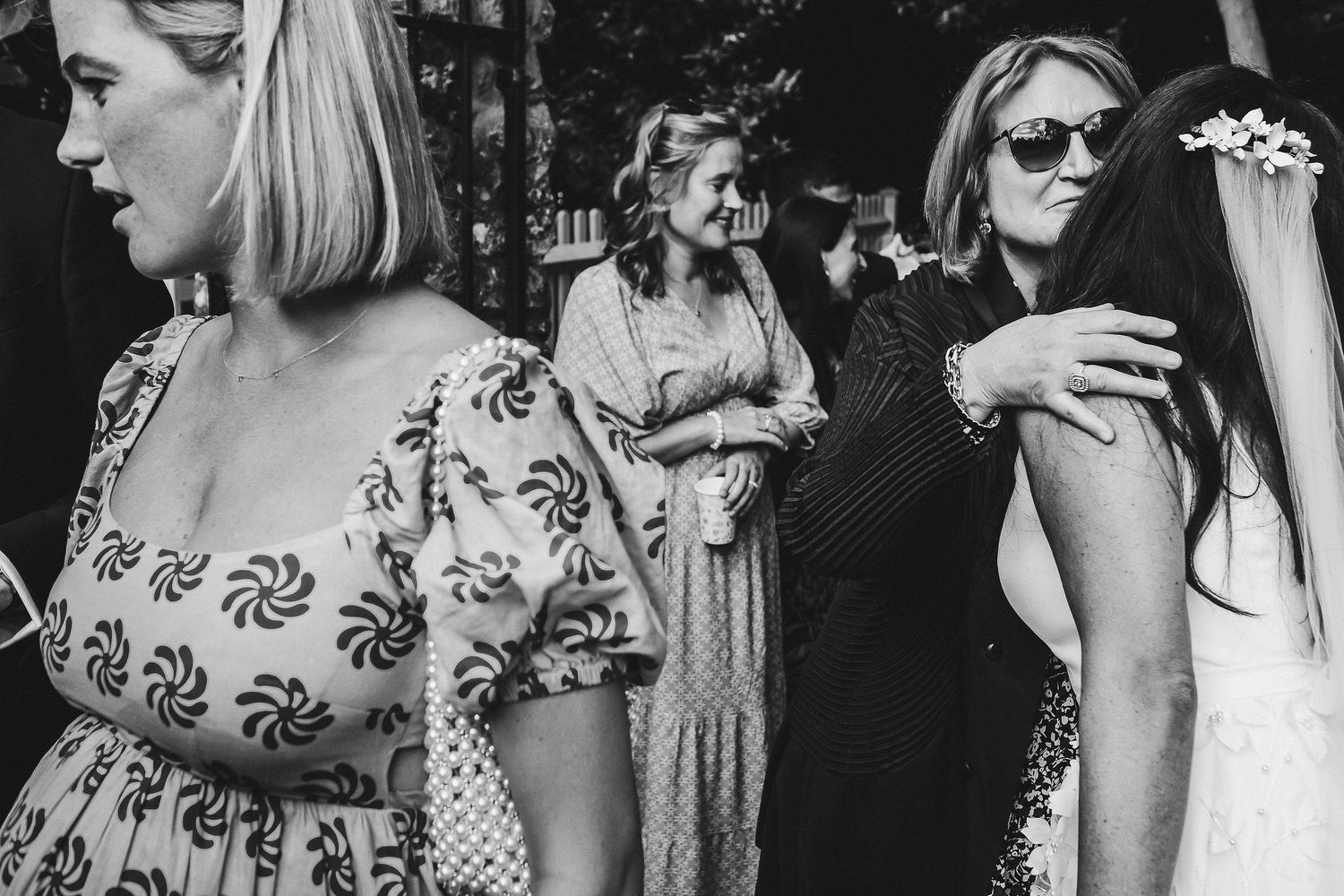 Black and white candid shot of wedding guests during outdoor celebration.