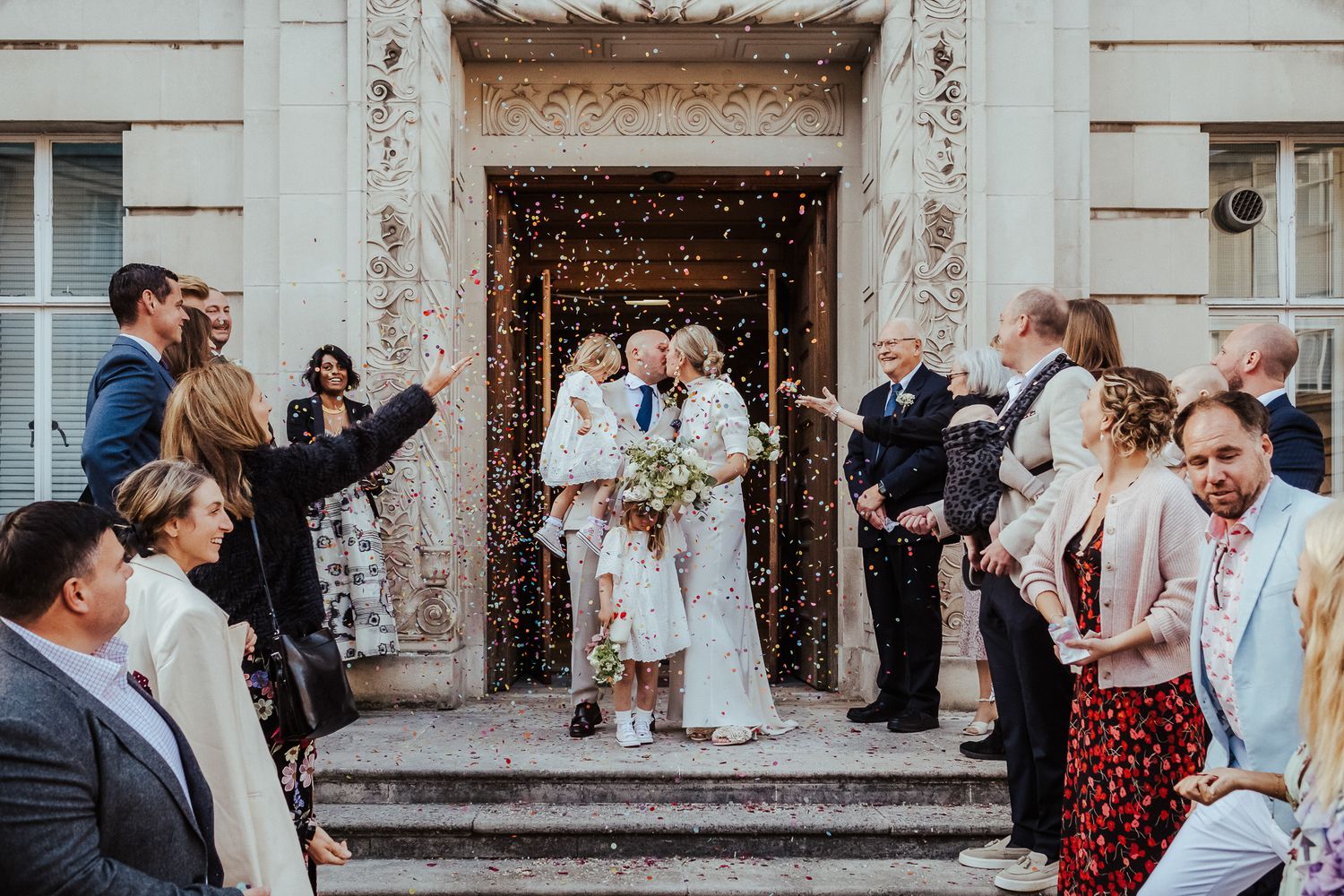 Wedding celebration with confetti and guests gathered on ornate marble steps.