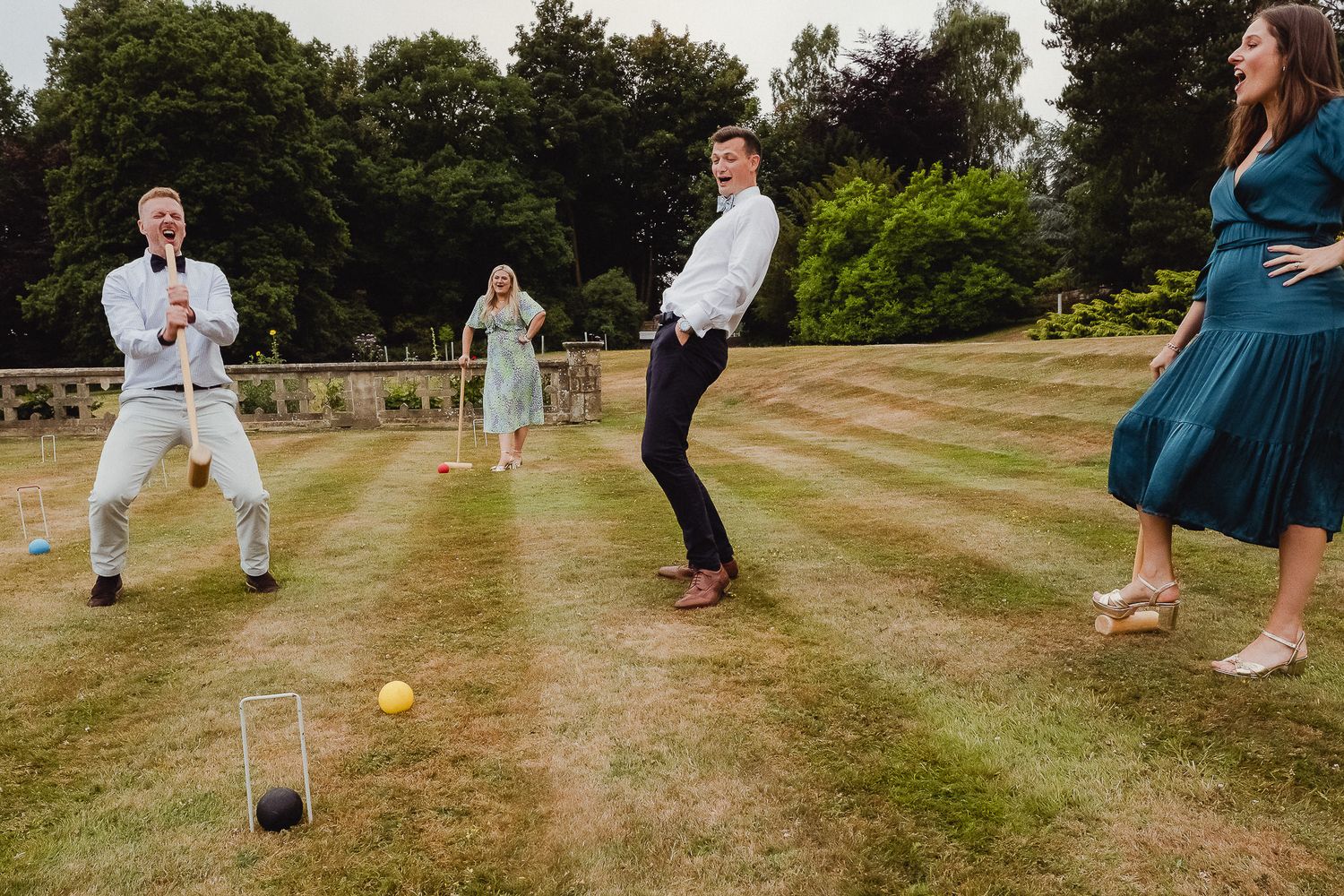 A group plays lawn bowling or bocce ball on a grassy hill during what appears to be a summer gathering.