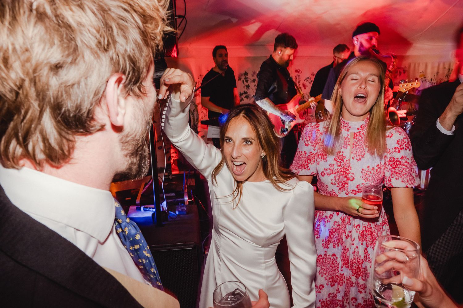 People dancing and having fun at a party with red lighting and energetic atmosphere.