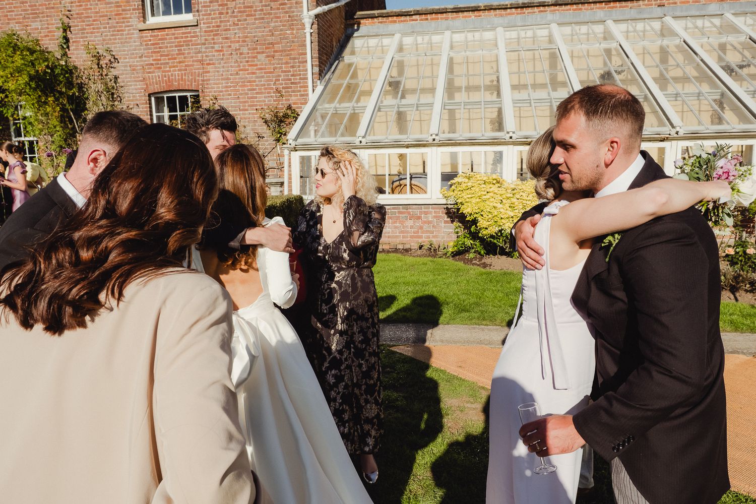 A series of wedding photos showing a couple sharing intimate moments in a garden setting with brick buildings in background.