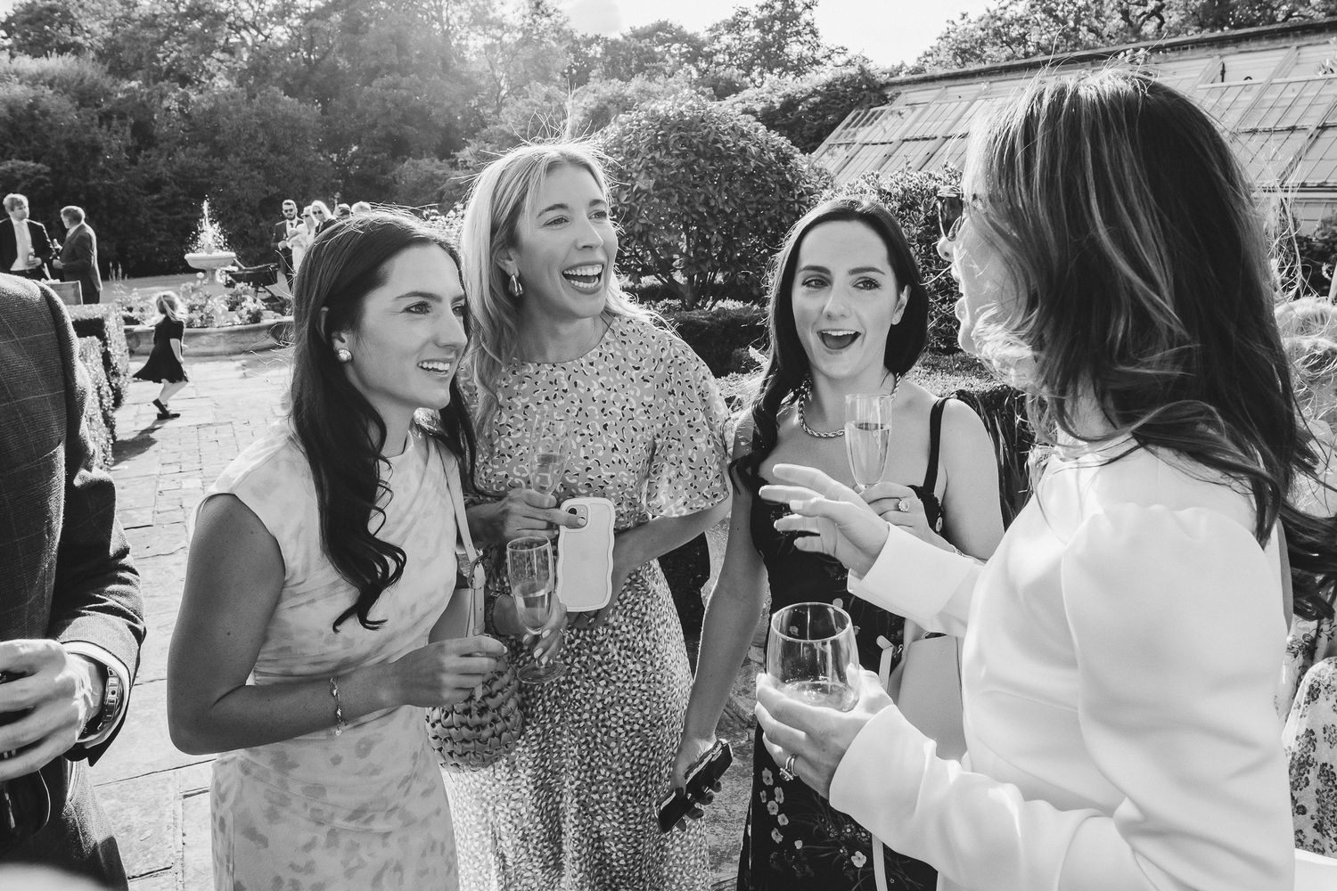 A group of people laughing and socializing at an outdoor gathering while holding drinks and enjoying themselves.
