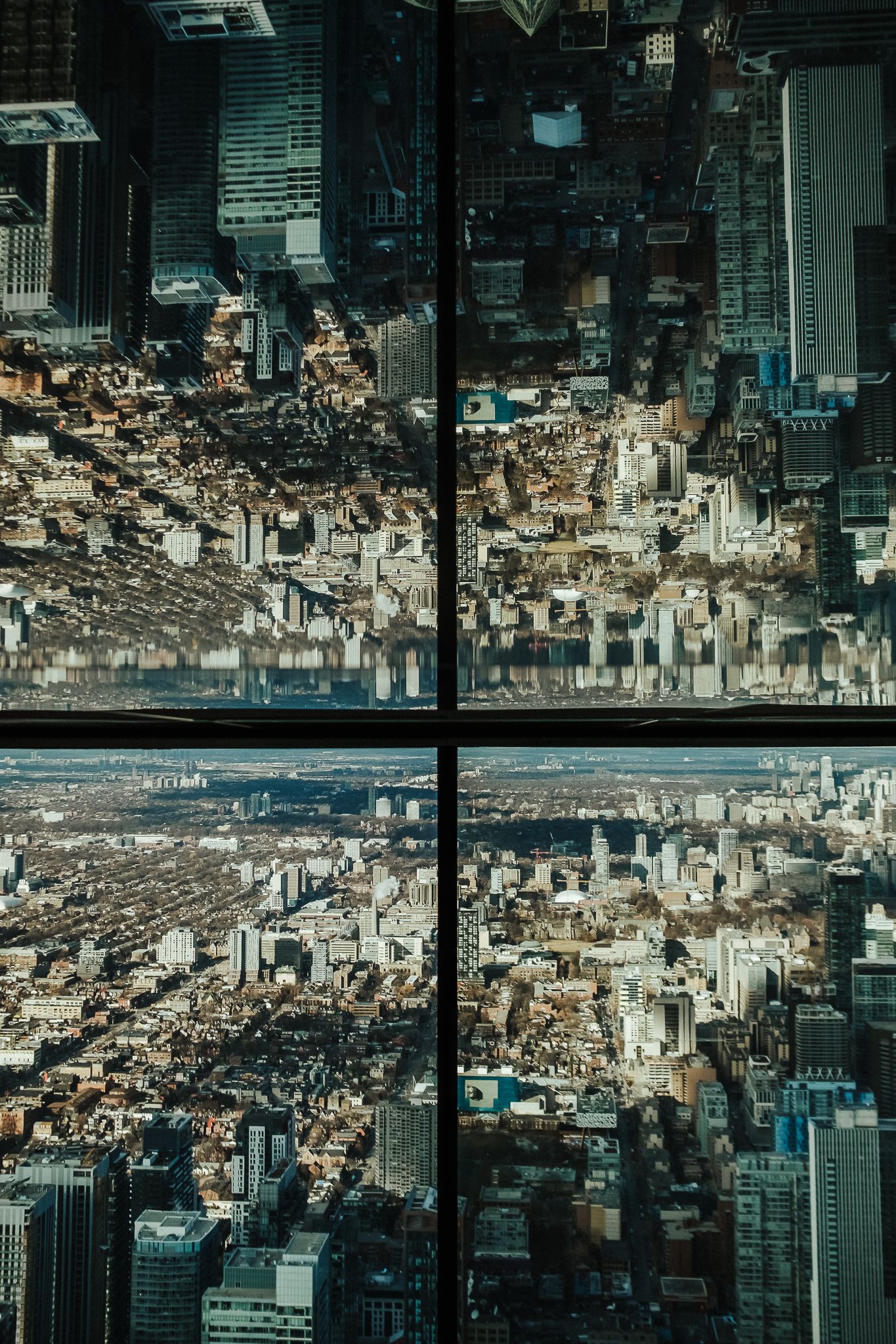 Upside down reflection of a modern cityscape with skyscrapers seen through large glass windows creating a mirror effect.
