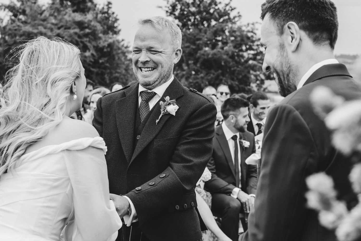 A black and white wedding photo collage showing joyful moments during an outdoor celebration.