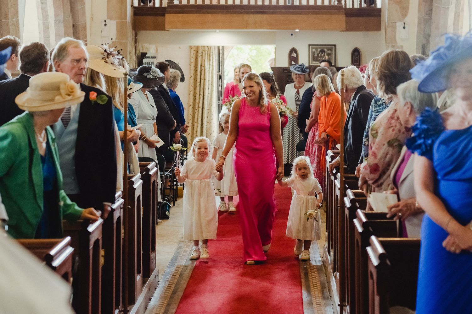 Wedding guests dance and celebrate together inside an elegant reception venue with wooden beams and festive lighting.