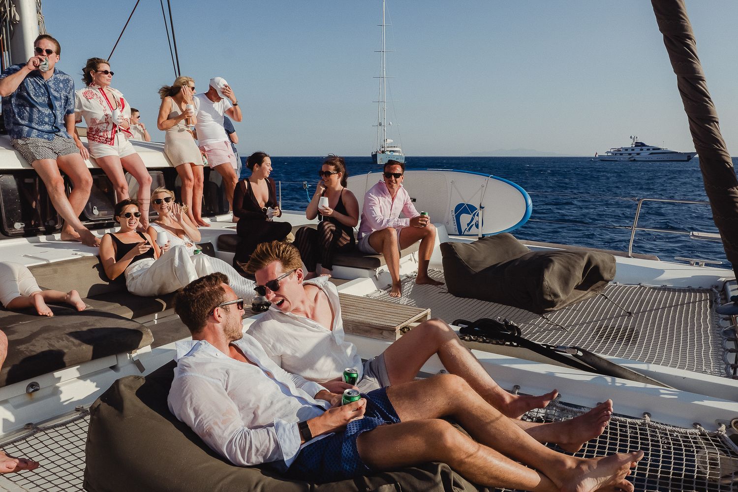 People relaxing and socializing together on a luxury sailboat deck while enjoying a sunny day at sea.