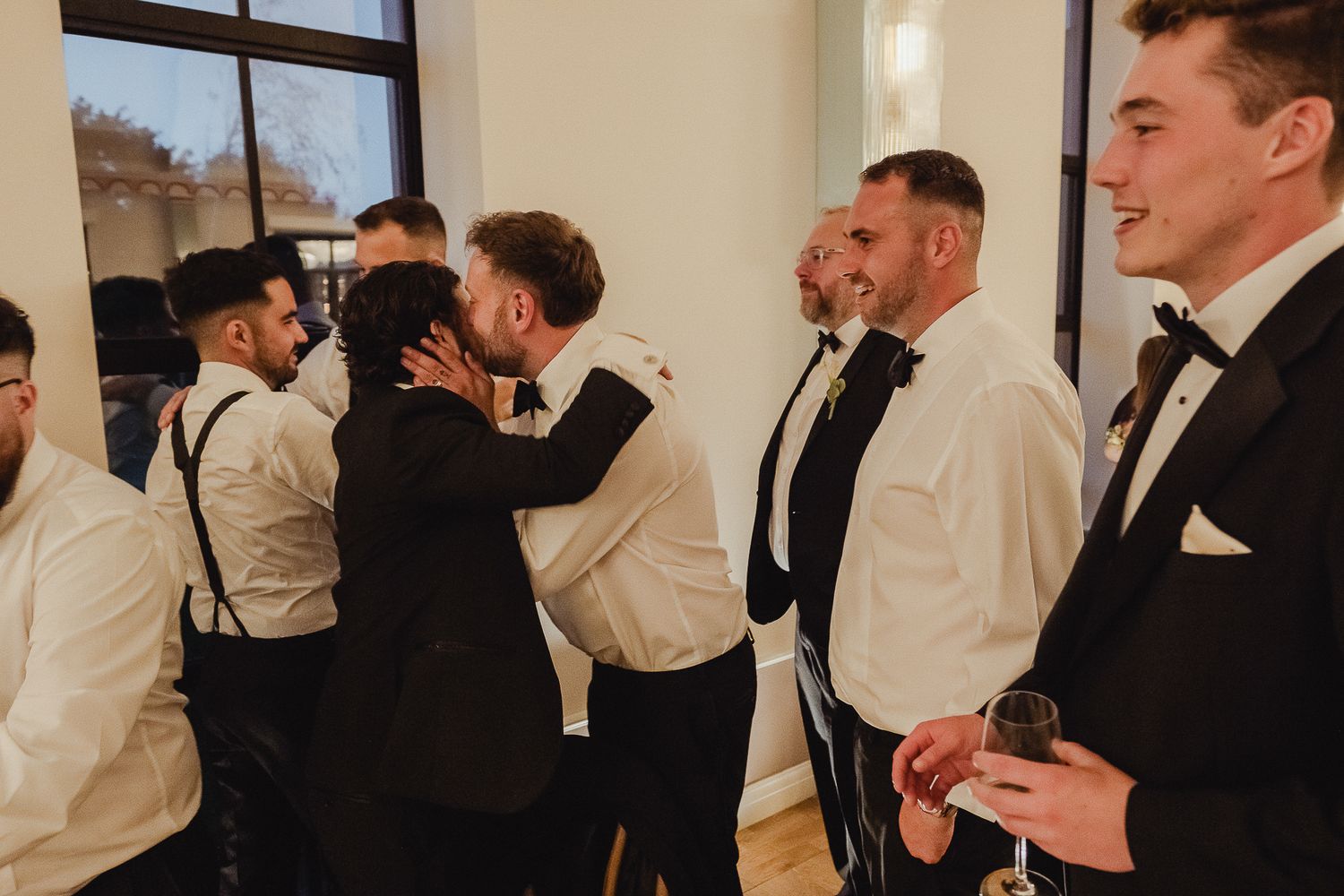 Wedding party members in white shirts and formal attire gather together during a celebration event.
