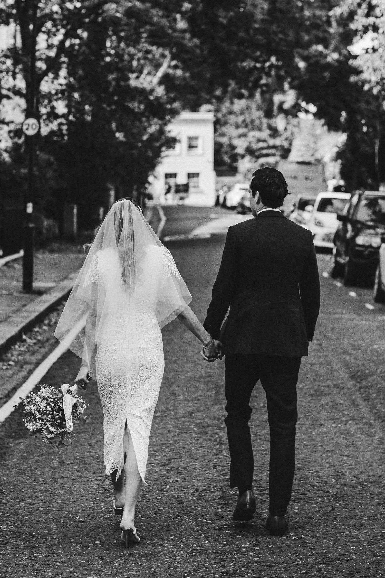 Black and white photo series showing a couple walking away from camera on a tree-lined path in wedding attire.