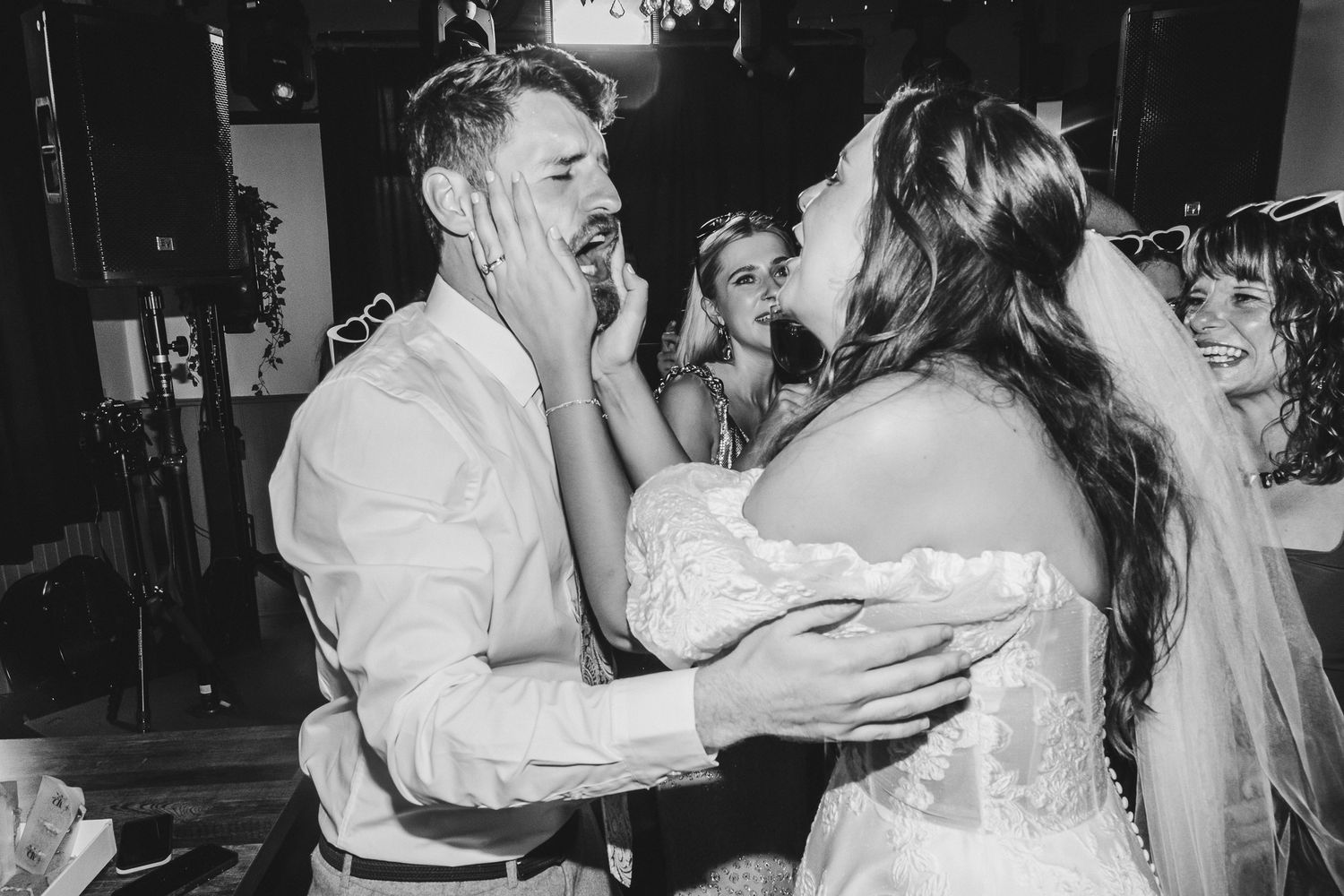Wedding guests dancing and celebrating together on a dimly lit dance floor at a reception party.