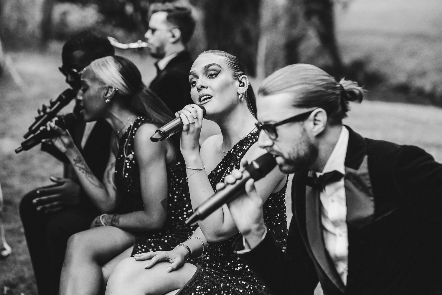 Wedding band performers sing into microphones during reception entertainment.