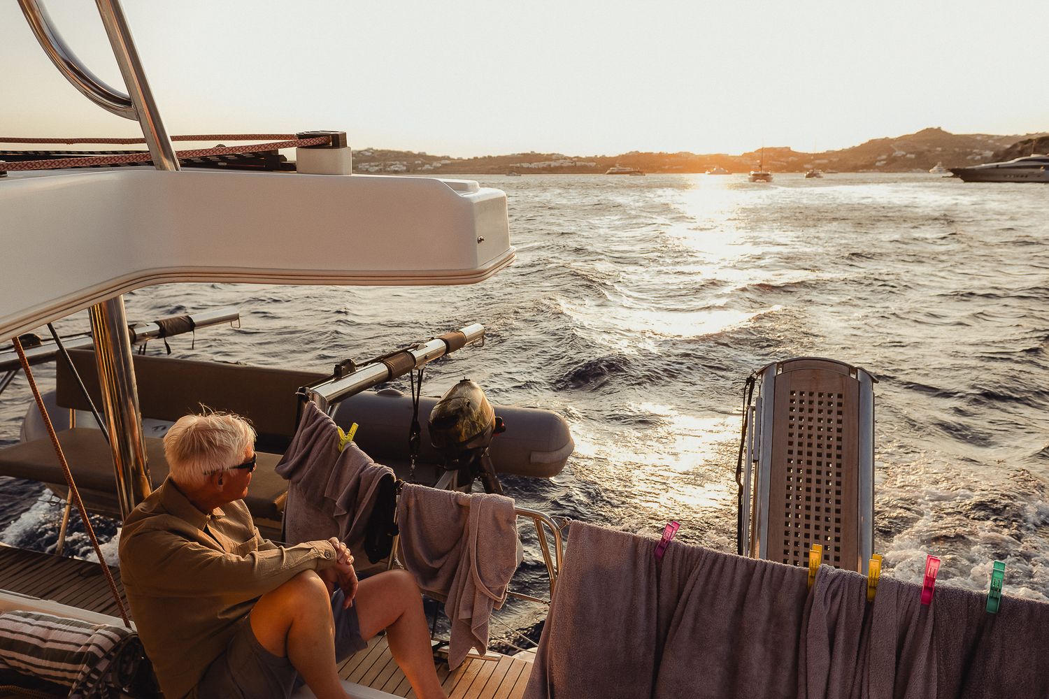 A couple enjoys watching a peaceful sunset together by the ocean on a wooden bench.