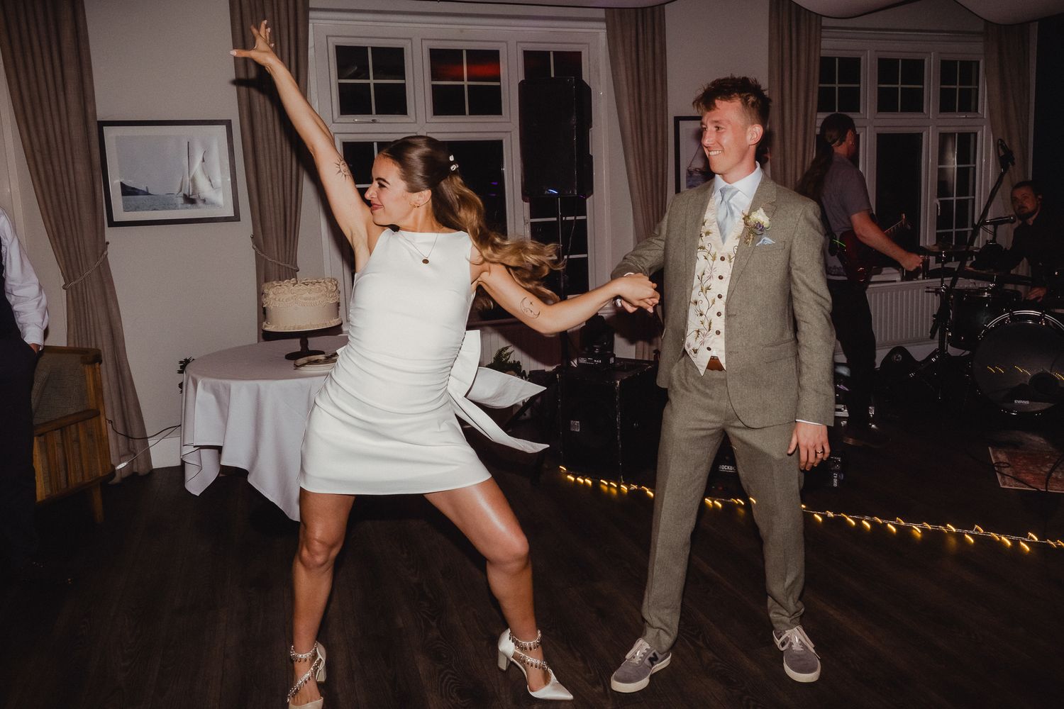 Wedding guests dance and celebrate on a dimly lit dance floor during an evening reception.