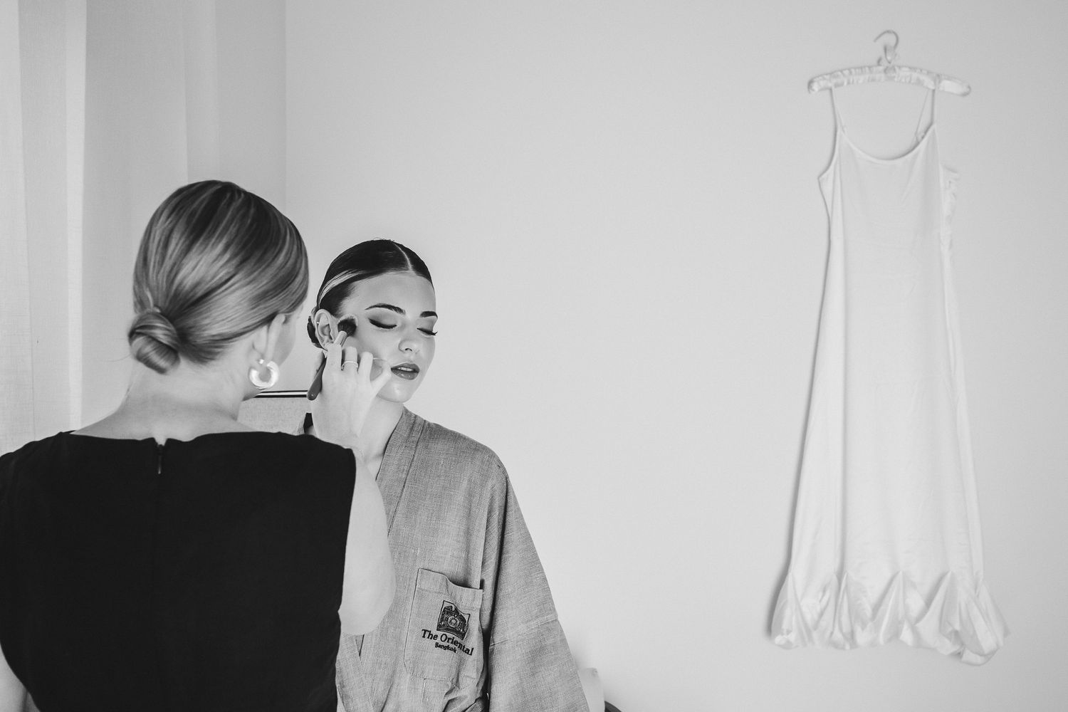 A series of black and white fashion photographs showing models posing in elegant dresses and outfits against a white wall.