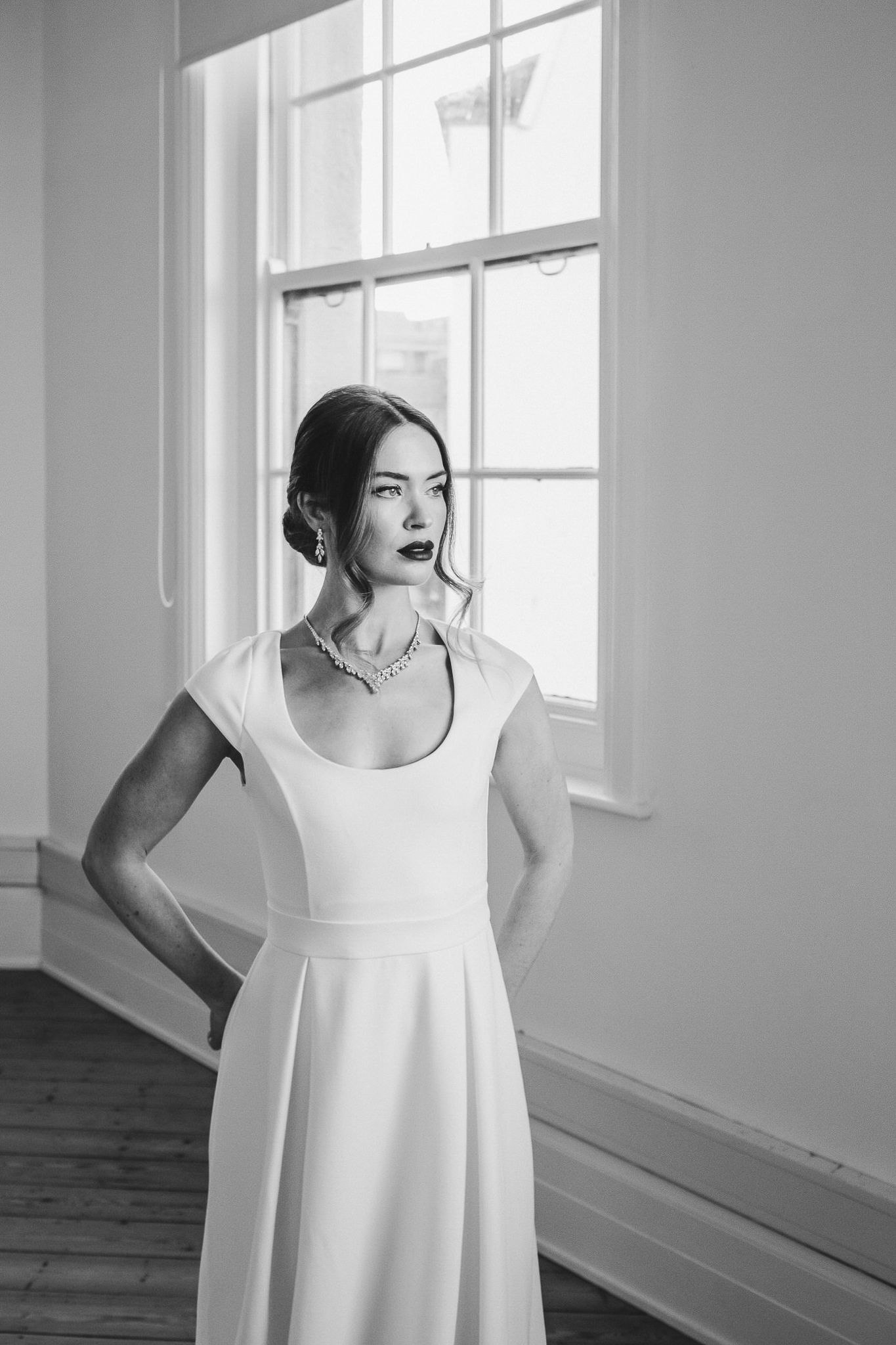 Black and white photos showing a person in a white sleeveless dress posing in a bright minimalist room.