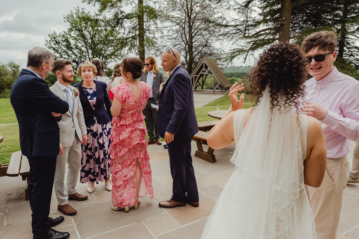 Wedding guests gather outside for a celebratory receiving line at an outdoor garden venue.