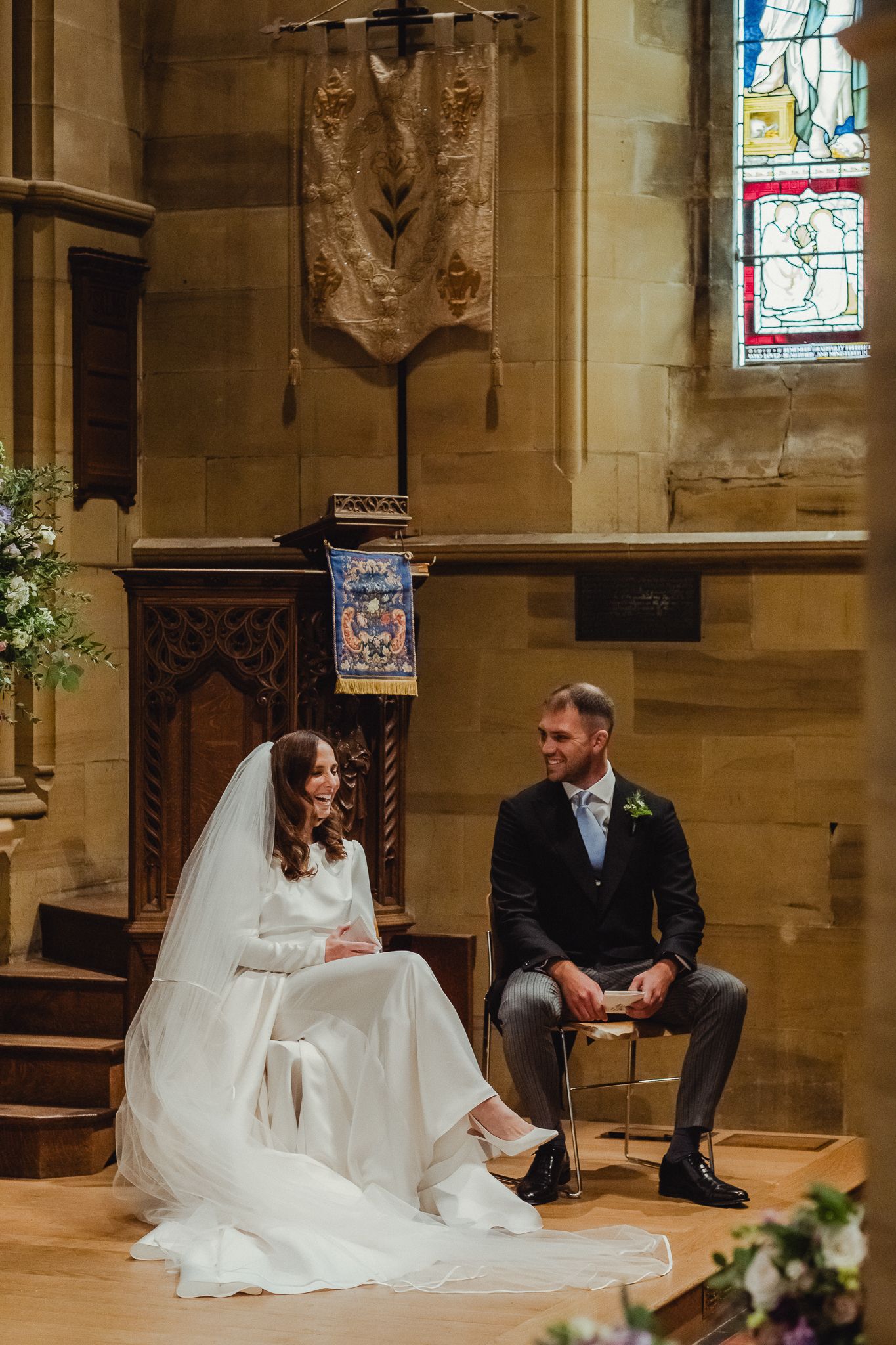 A series of candid wedding moments showing a couple sitting and interacting in a stone church with stained glass windows.