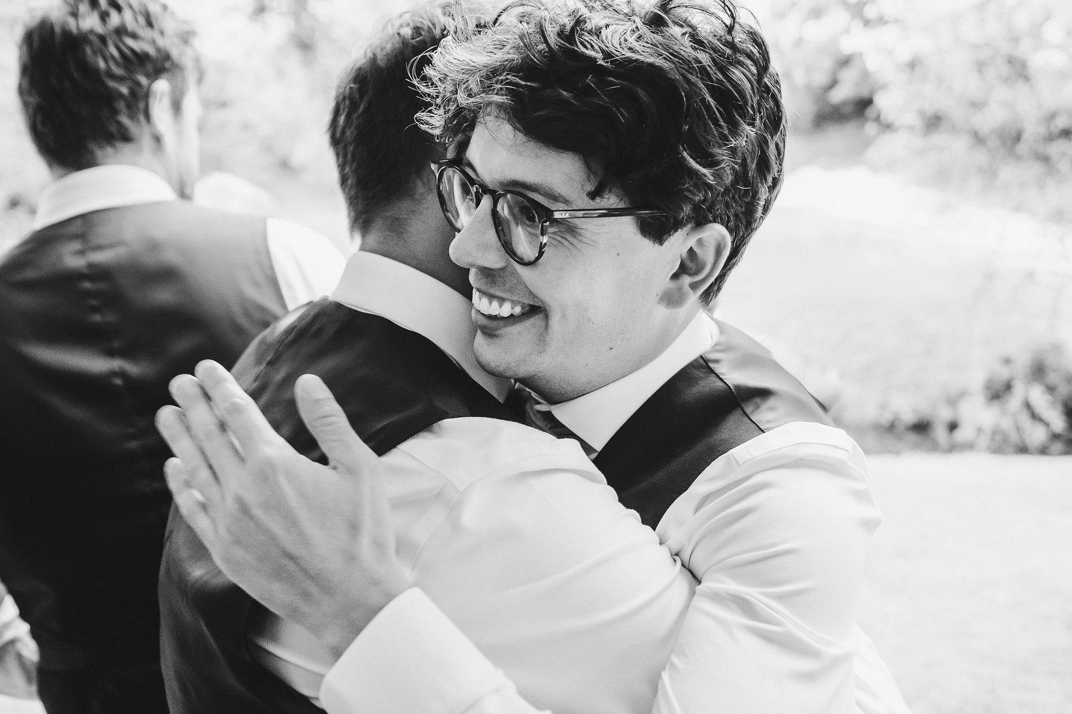 Black and white photo showing joyful embrace during wedding celebration.