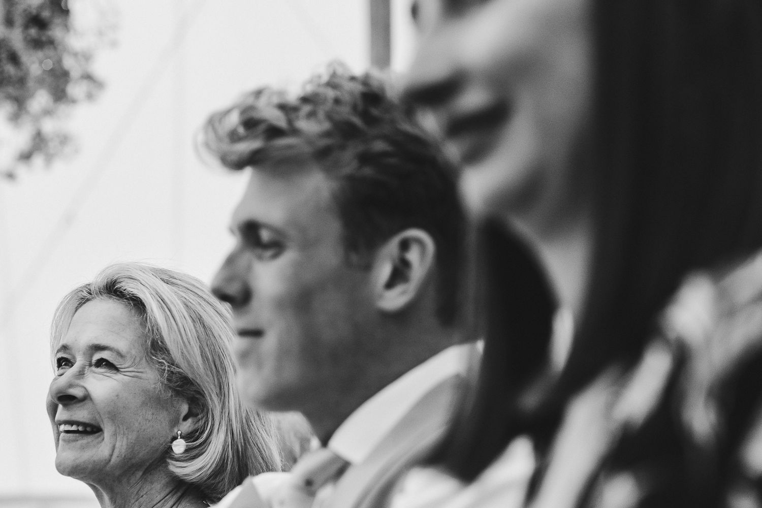 Black and white photo captures genuine reactions during emotional wedding reception toasts.