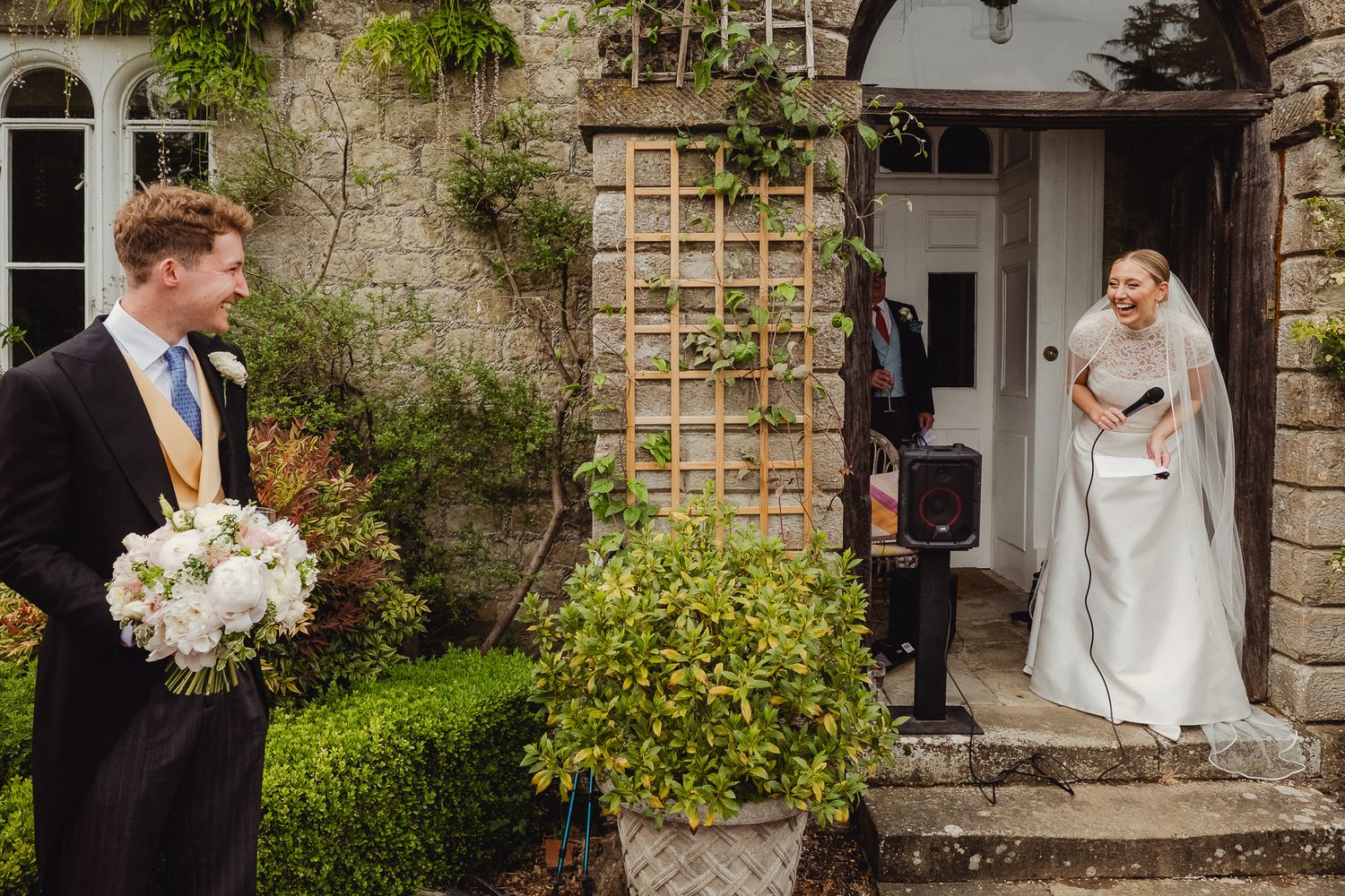 Elegant wedding scene at a stone garden cottage with trailing vines and flowers creating a romantic atmosphere.