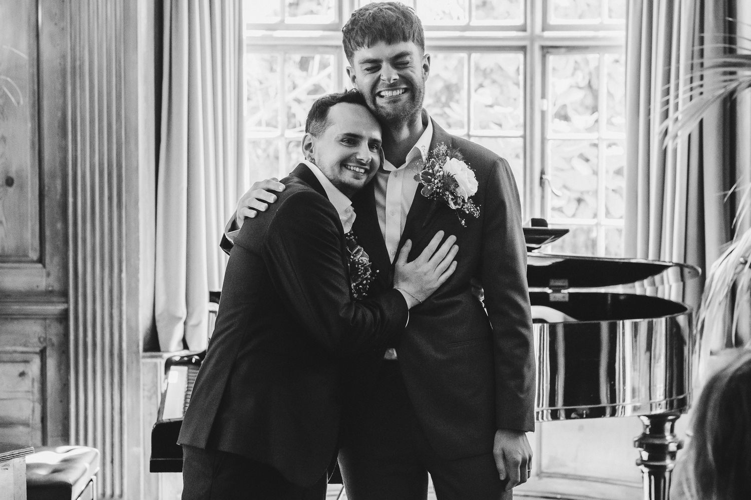 A black and white candid photo of a joyful couple sharing a happy moment together in an elegant indoor setting.