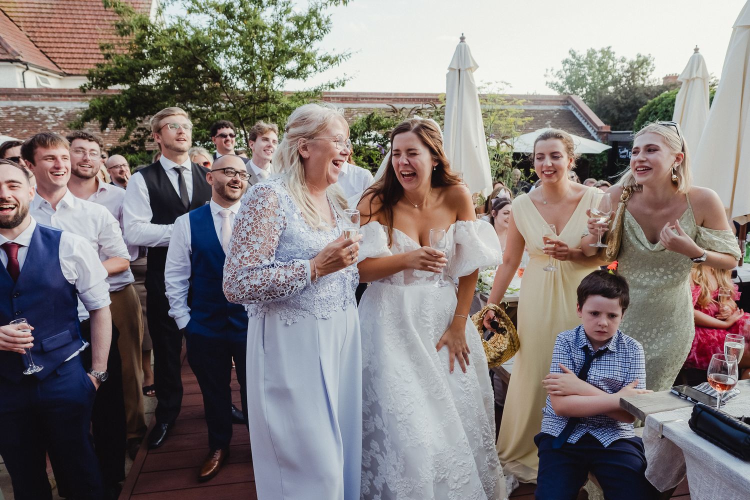 Wedding guests dance and celebrate during an outdoor reception on a sunny summer day.