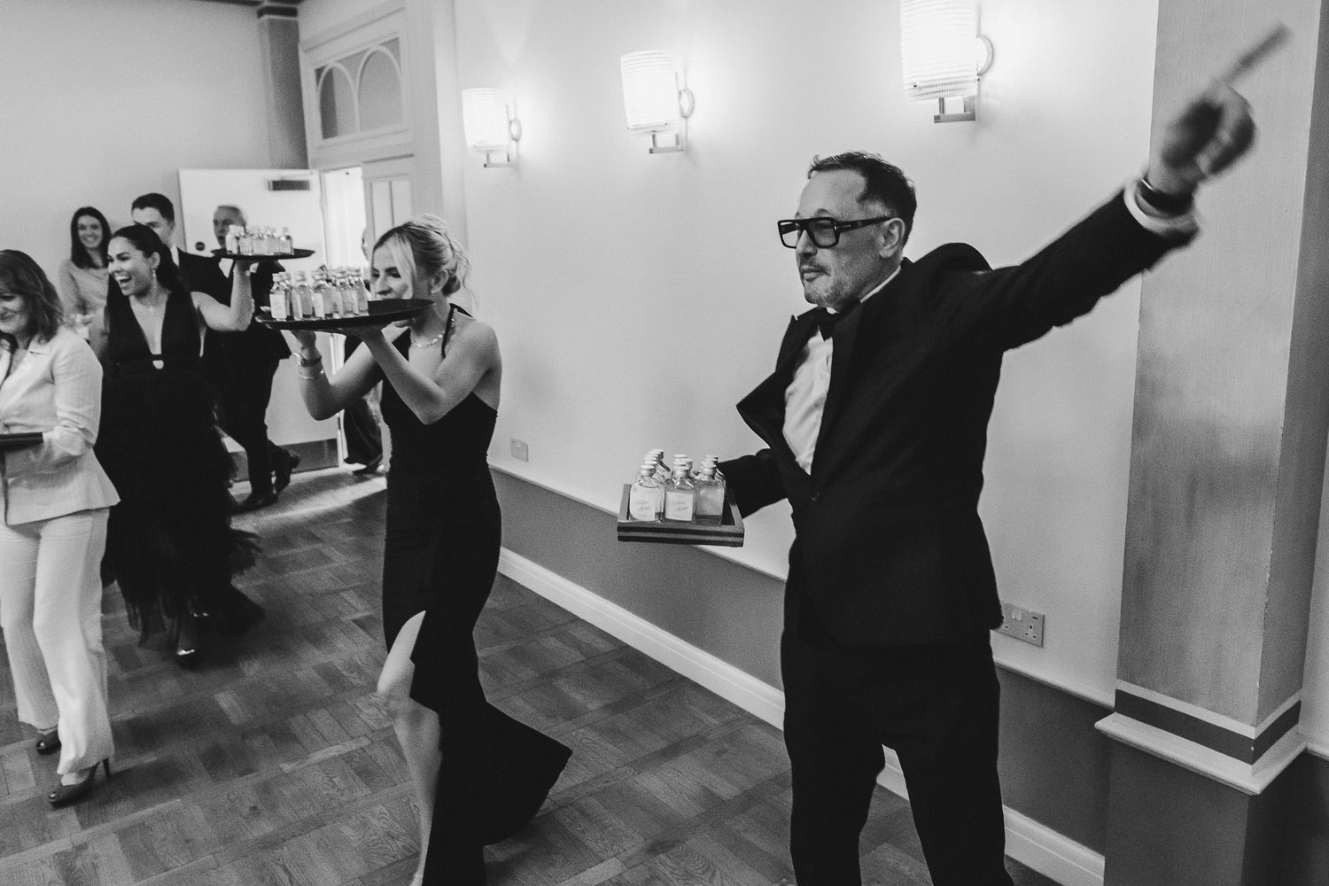 A group of people in formal attire dancing and celebrating at a wedding reception party.