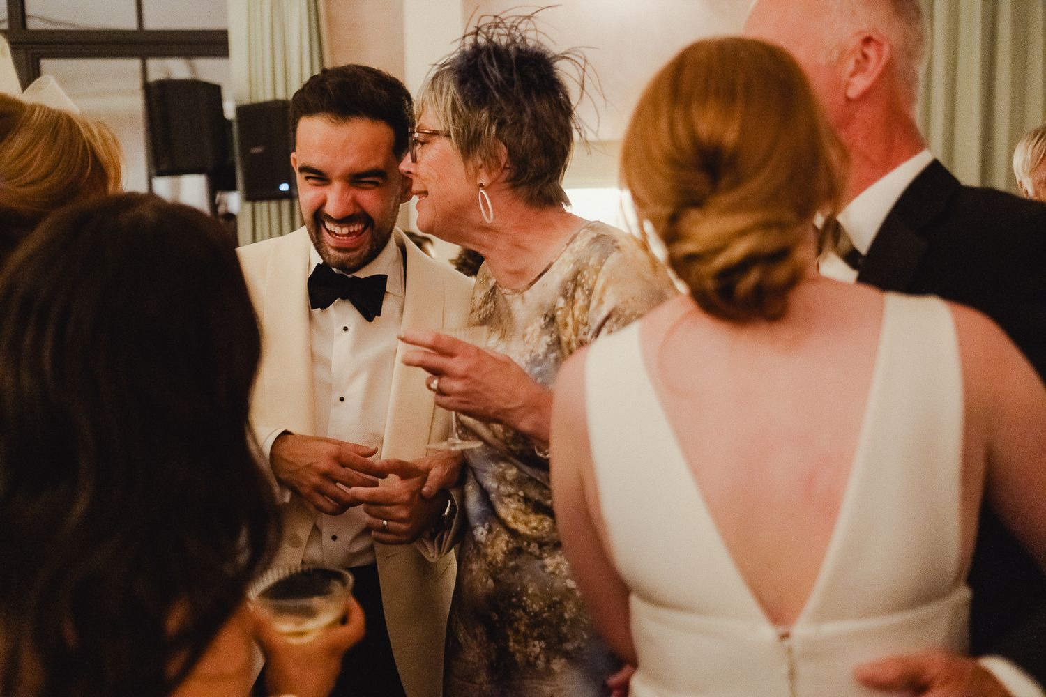 Wedding guests share joyful laughter during an intimate reception celebration.