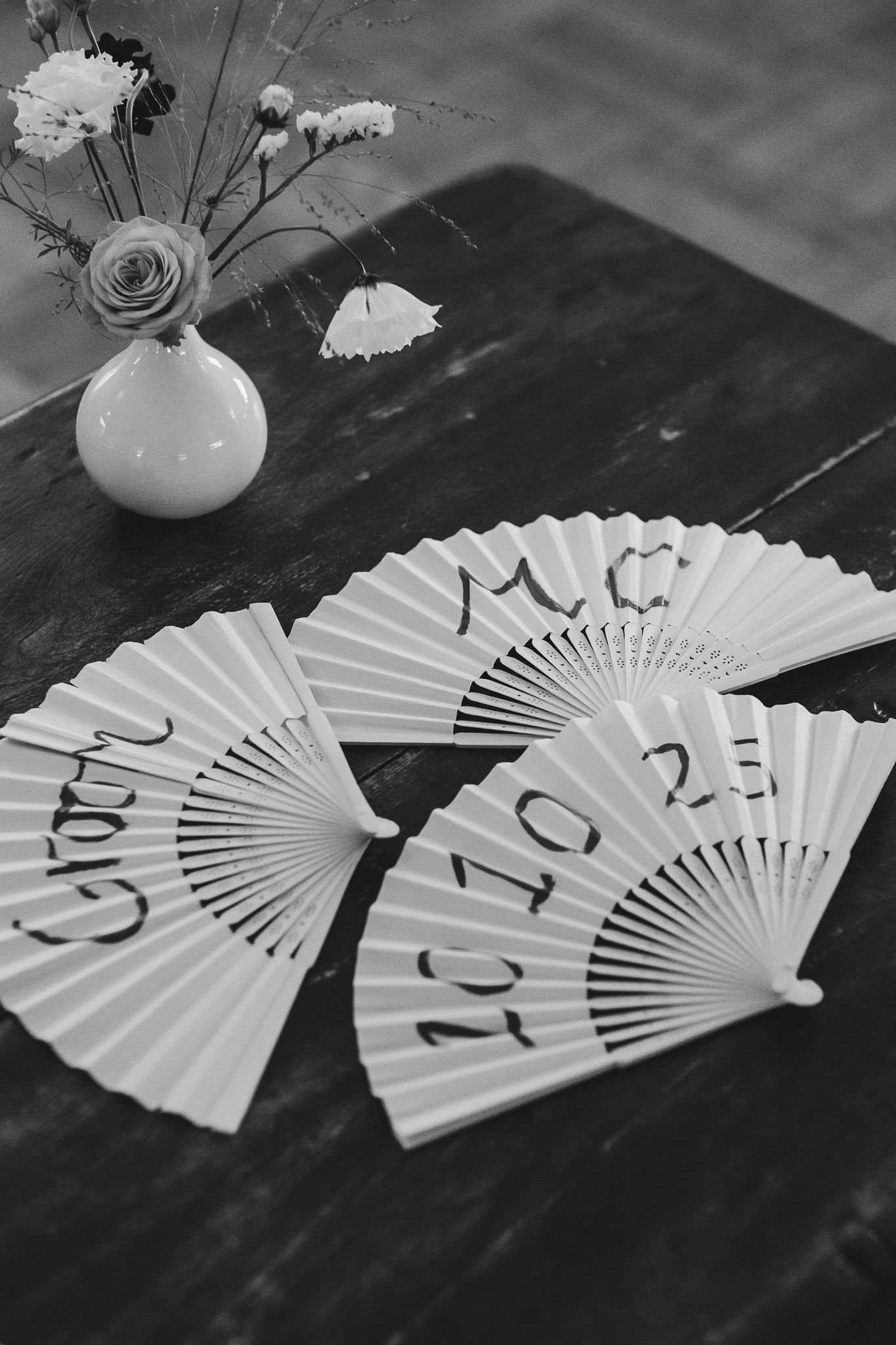 A series of white paper fans with numbers arranged in sequence on a dark surface in black and white photography.