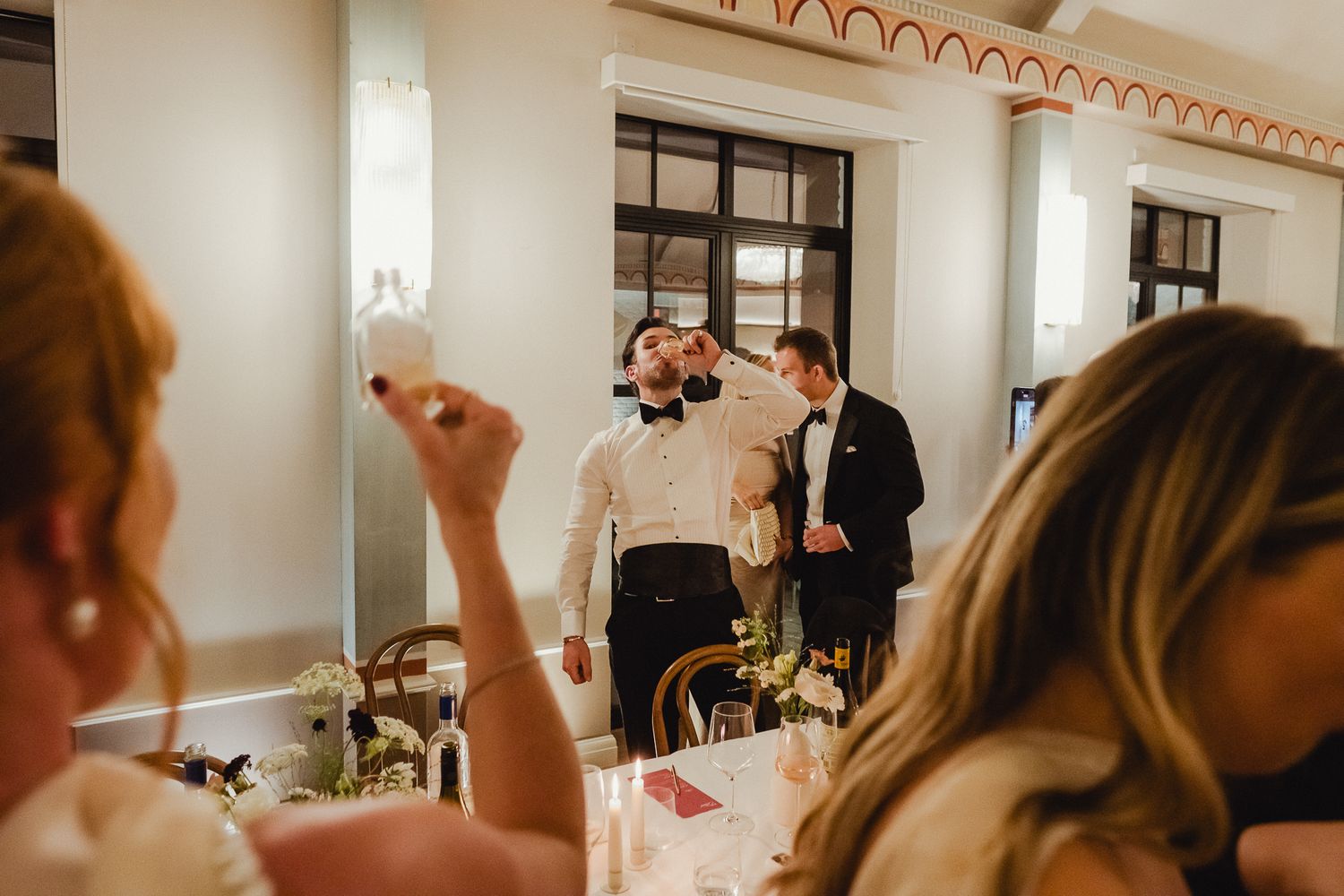 Someone applies makeup in front of a mirror during wedding preparations in a bright, elegant room.