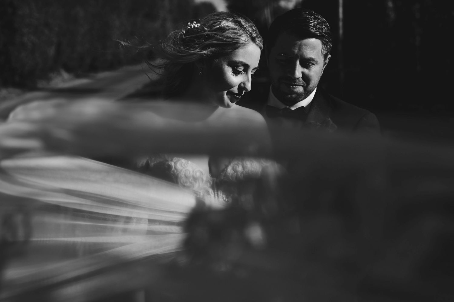 Artistic black and white portrait through wedding veil in dramatic lighting.