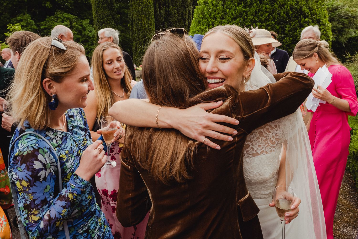 Joyful embraces and hugs among wedding guests during an outdoor celebration in a garden setting.