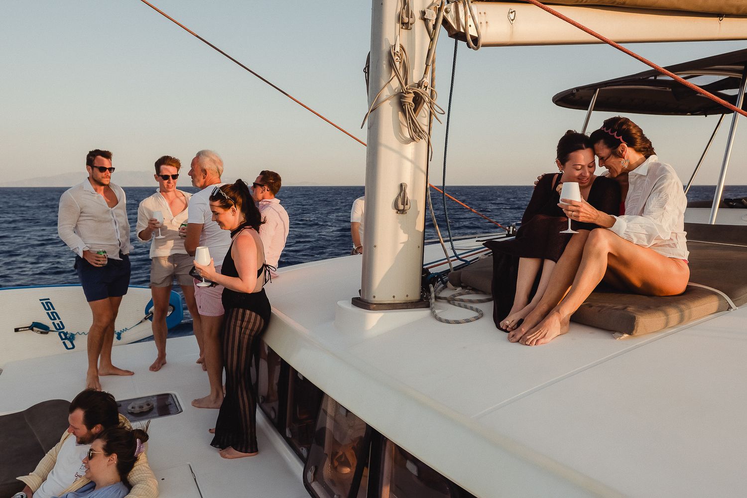 People enjoying leisure time aboard a sailing yacht during sunset hours in coastal waters.