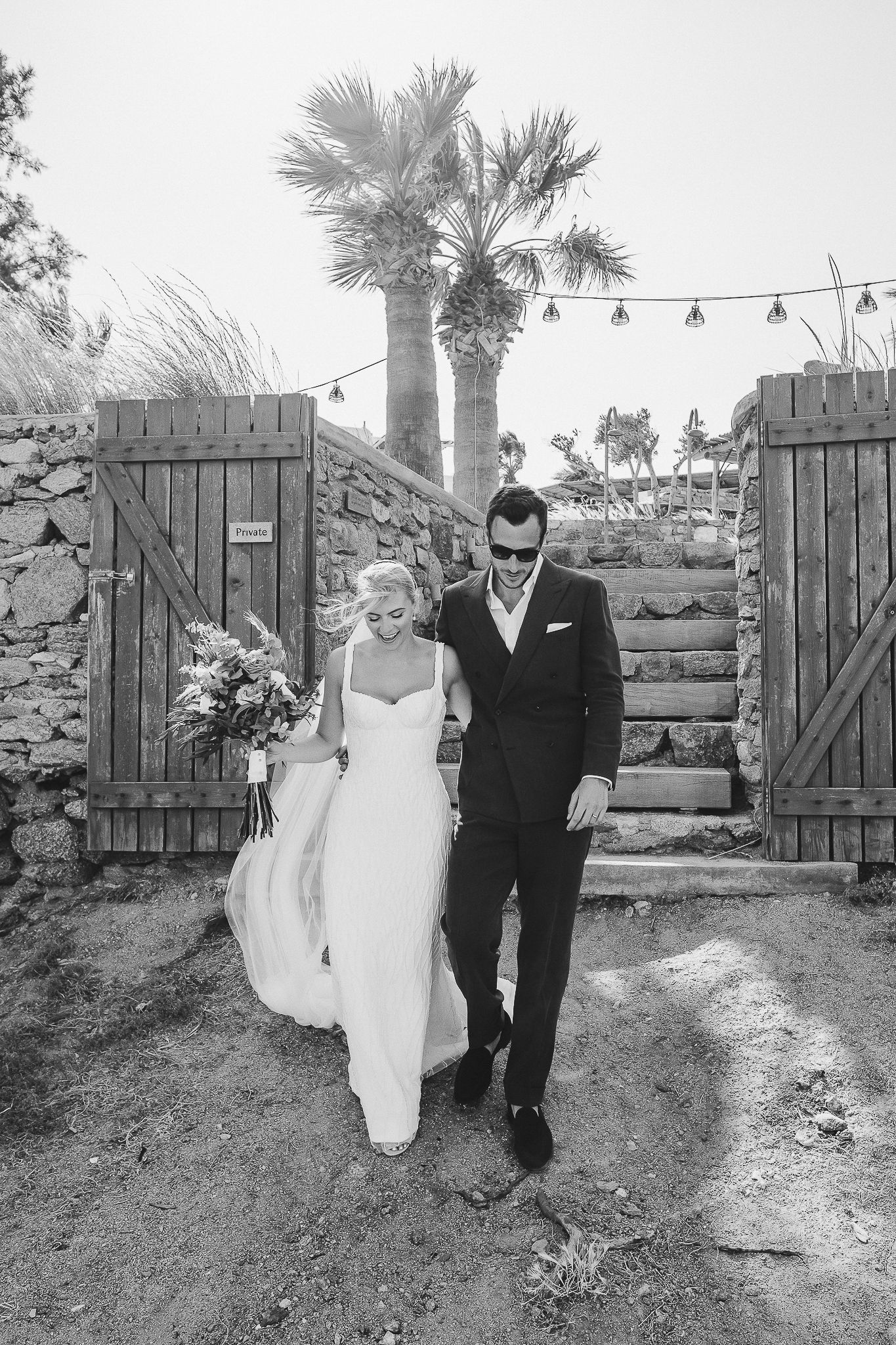 A black and white sequence of wedding photos in front of a rustic wooden fence and palm trees.