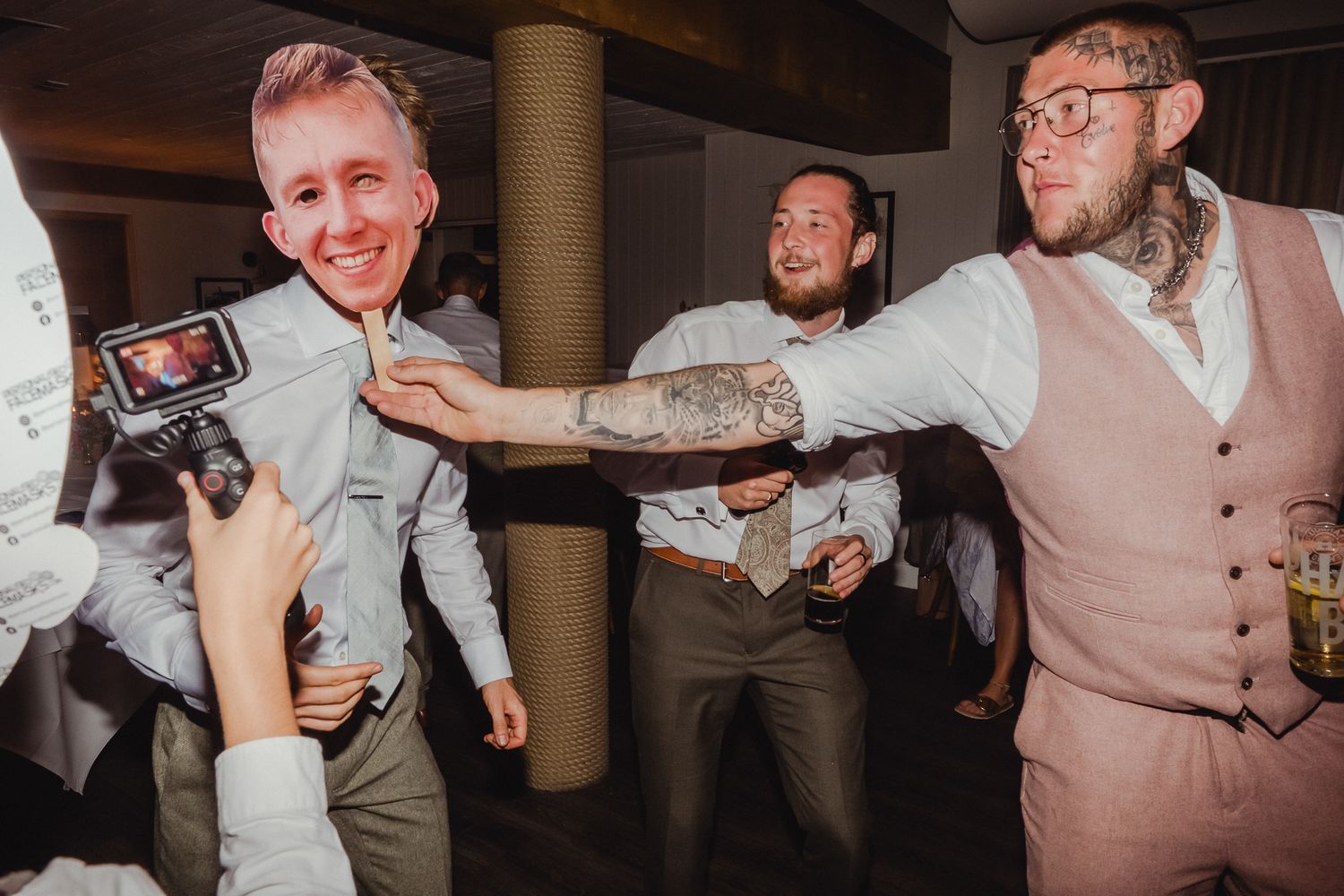 A group of people dancing and celebrating at a wedding reception in an indoor venue.