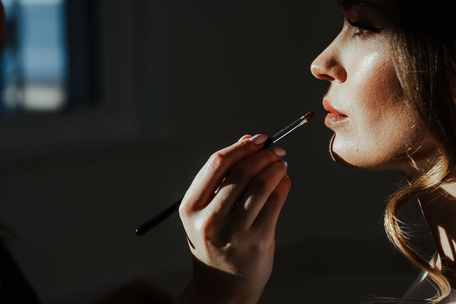 Person smoking a cigarette in a dark moody setting with dramatic lighting and shadows.