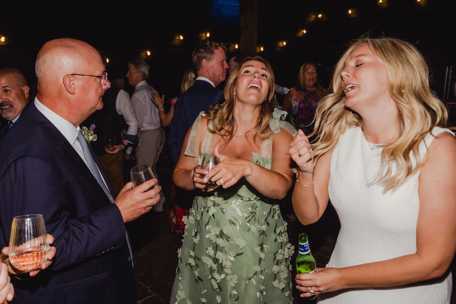 A group of people enjoying drinks and laughing together at an evening social gathering.