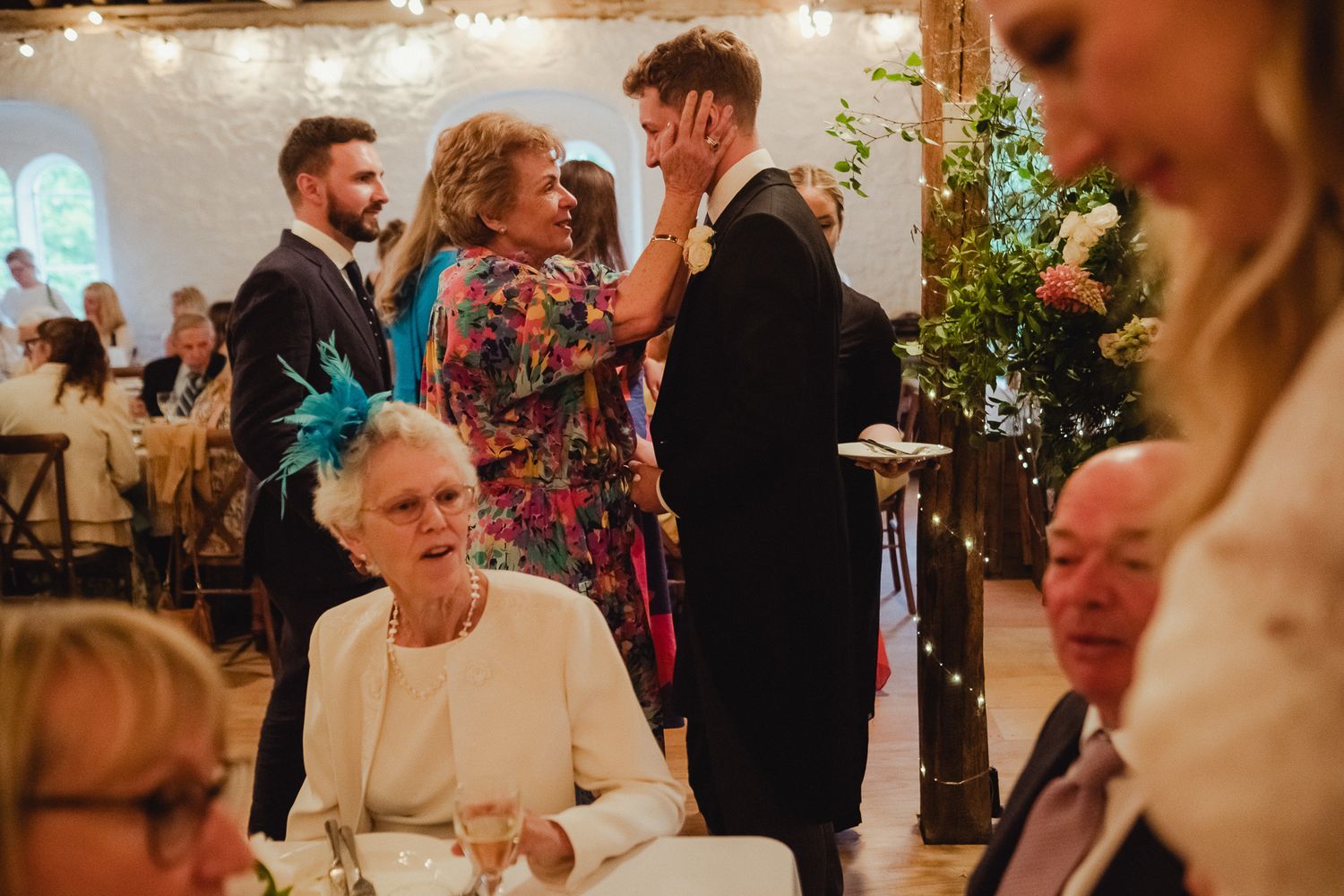Wedding guests enjoy candid moments and celebrate during an indoor reception at a rustic venue.