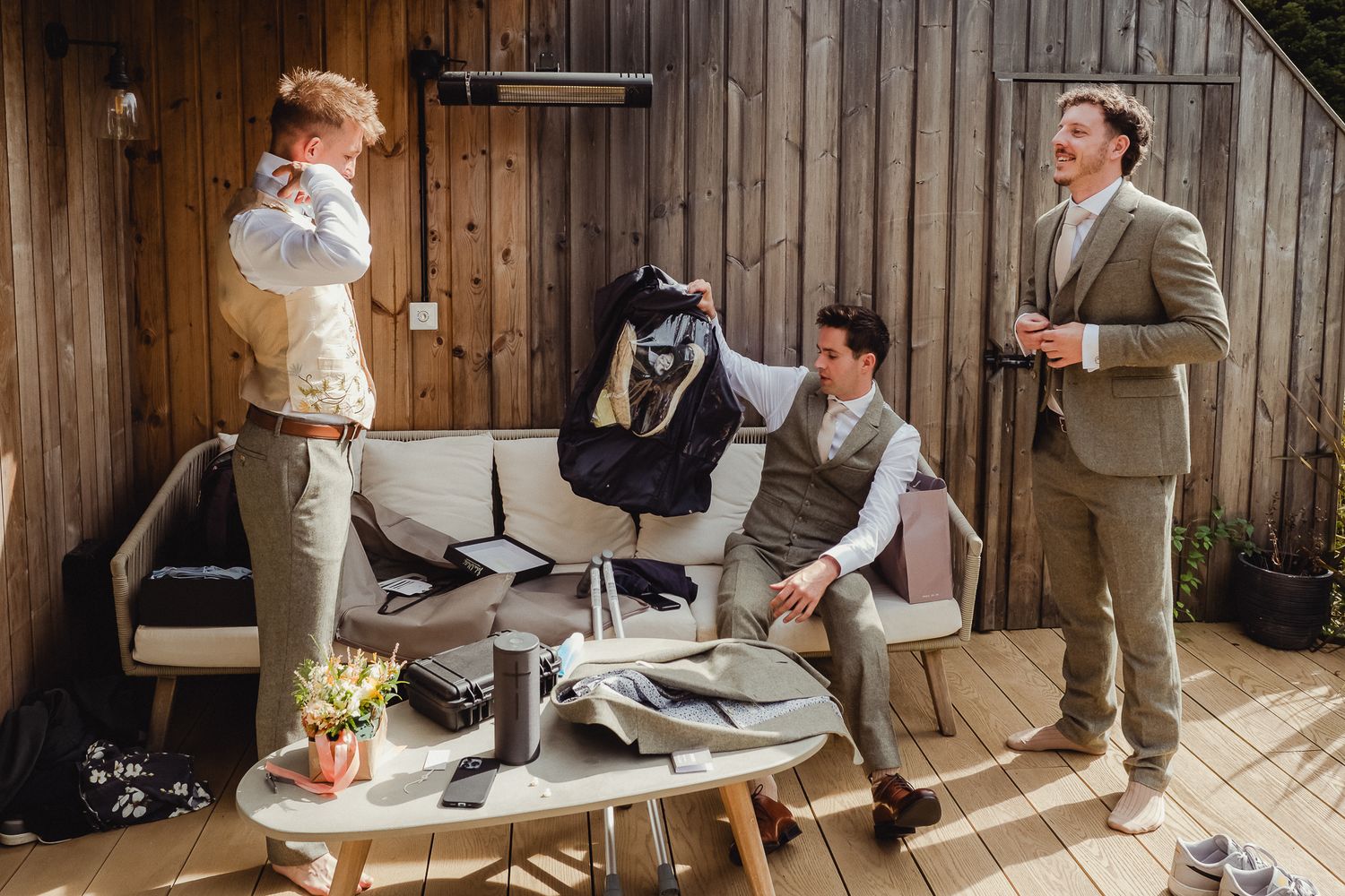 Wedding party members sign documents at a rustic wooden venue during a ceremony.