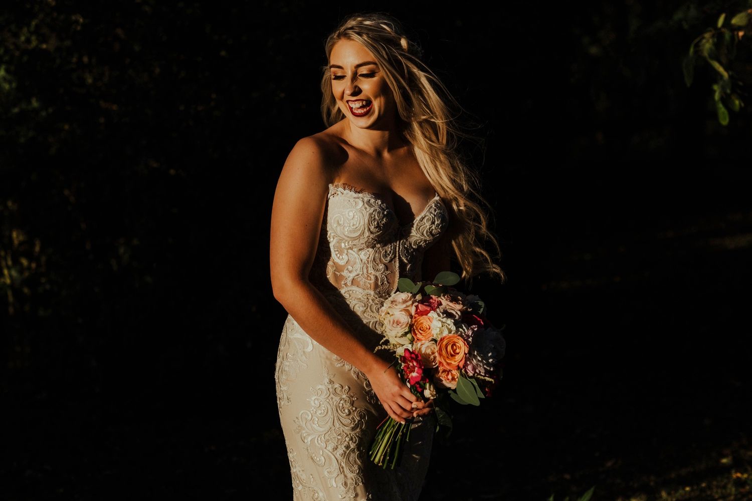 Wedding portrait session with dramatic lighting against dark background.