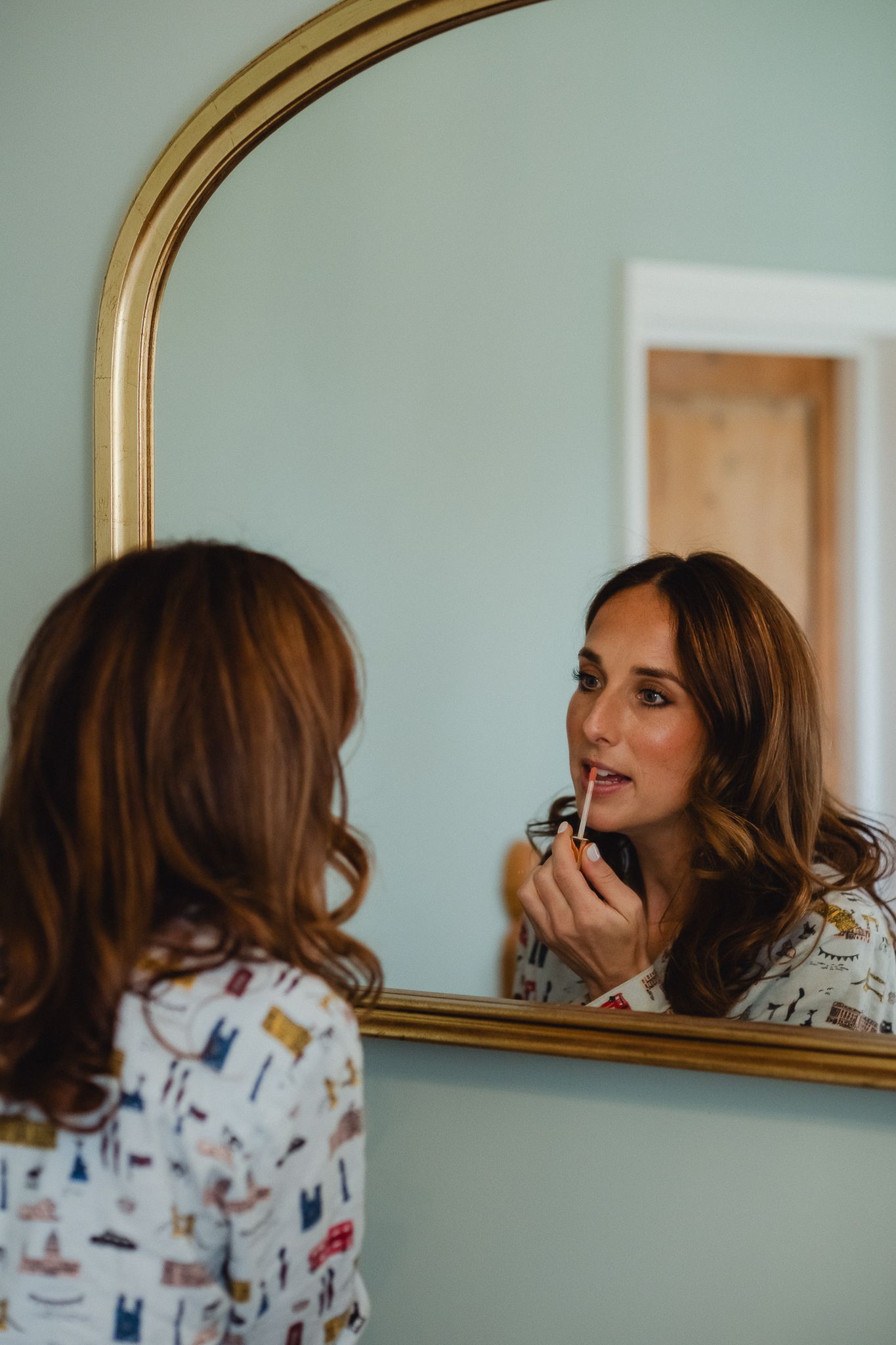 A sequence of reflections in an oval gold-framed mirror showing someone adjusting their hair against a mint green wall.