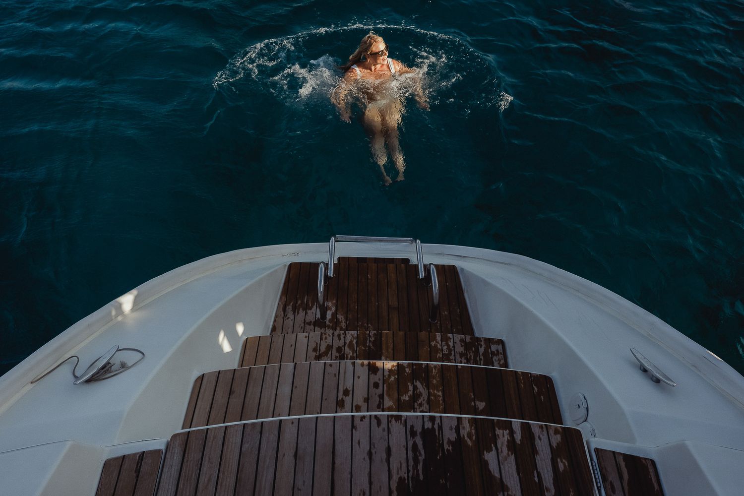 Aerial view of a luxury yacht sailing through dark blue ocean waters with white wake trailing behind.