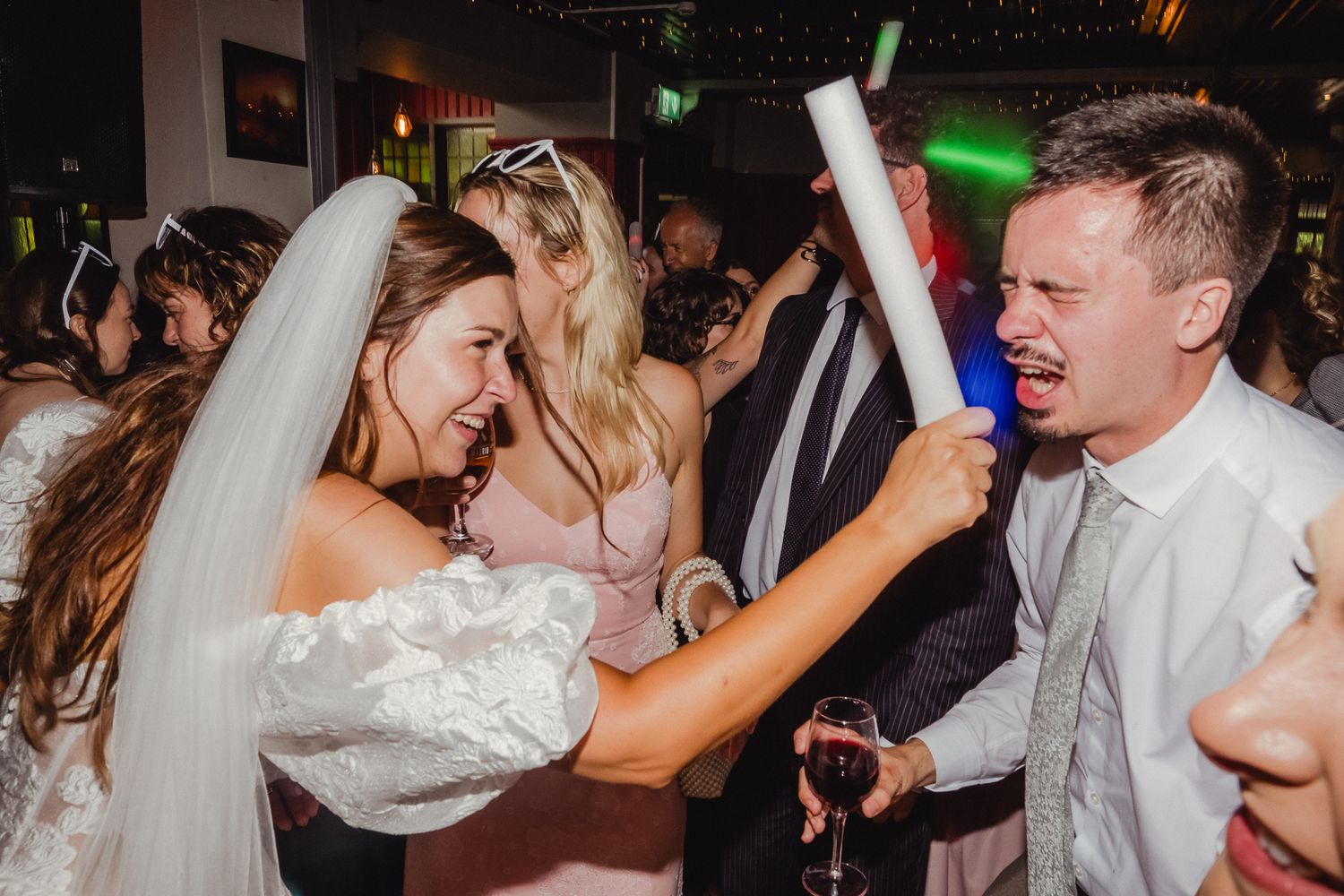 Wedding guests dance and celebrate together on a lively dance floor at an evening reception.
