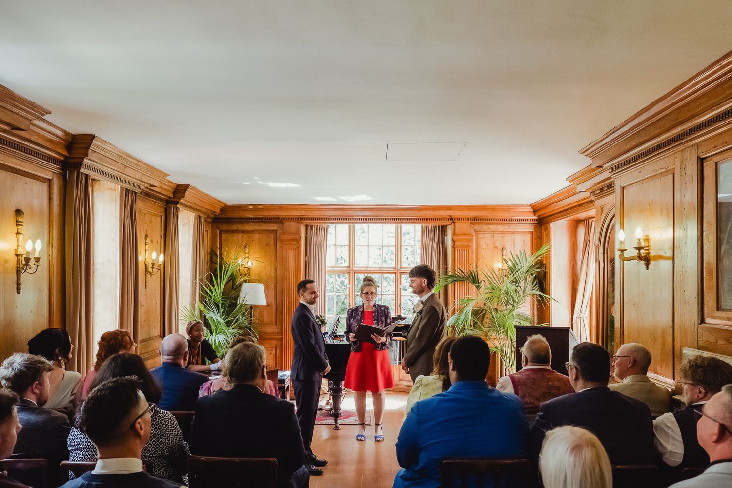 People gather in a wood-paneled room for a presentation or meeting with warm lighting and elegant decor.