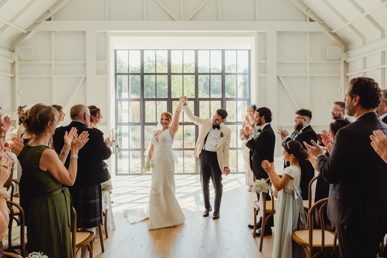 A panoramic view of a bright wedding reception venue with guests mingling in a white industrial-style space.