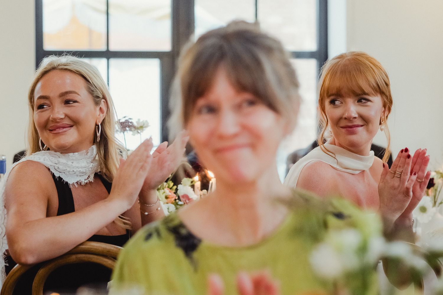 A group of people sitting at a long table smiling and celebrating during a social gathering.