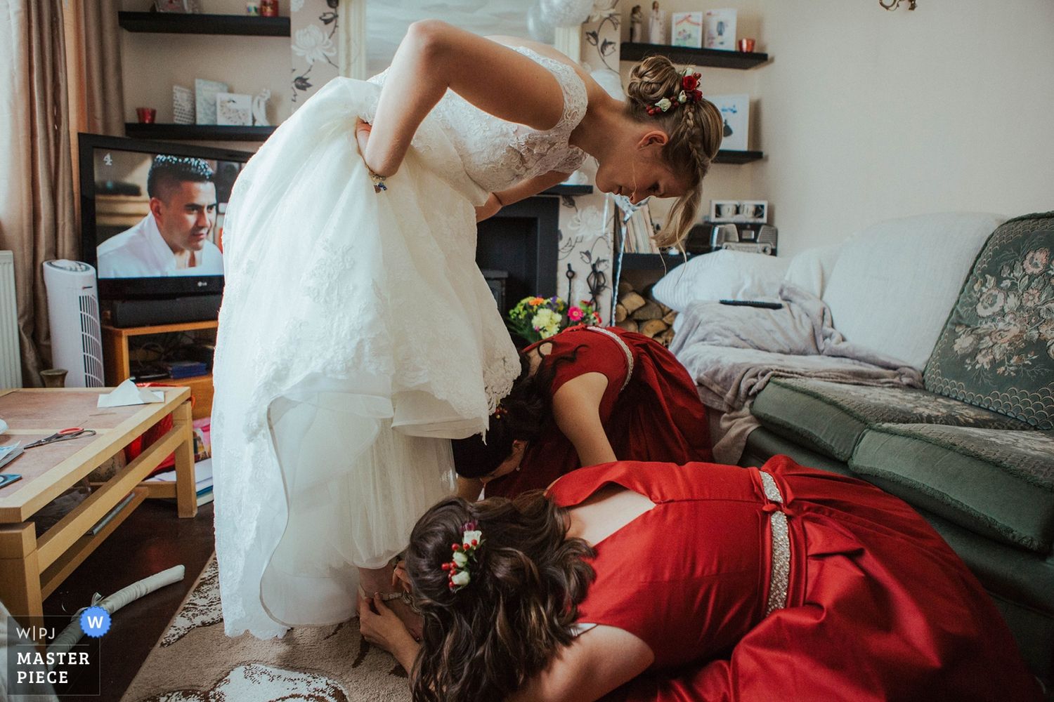 Getting ready scene shows bride in white dress with red accents during wedding day preparations.