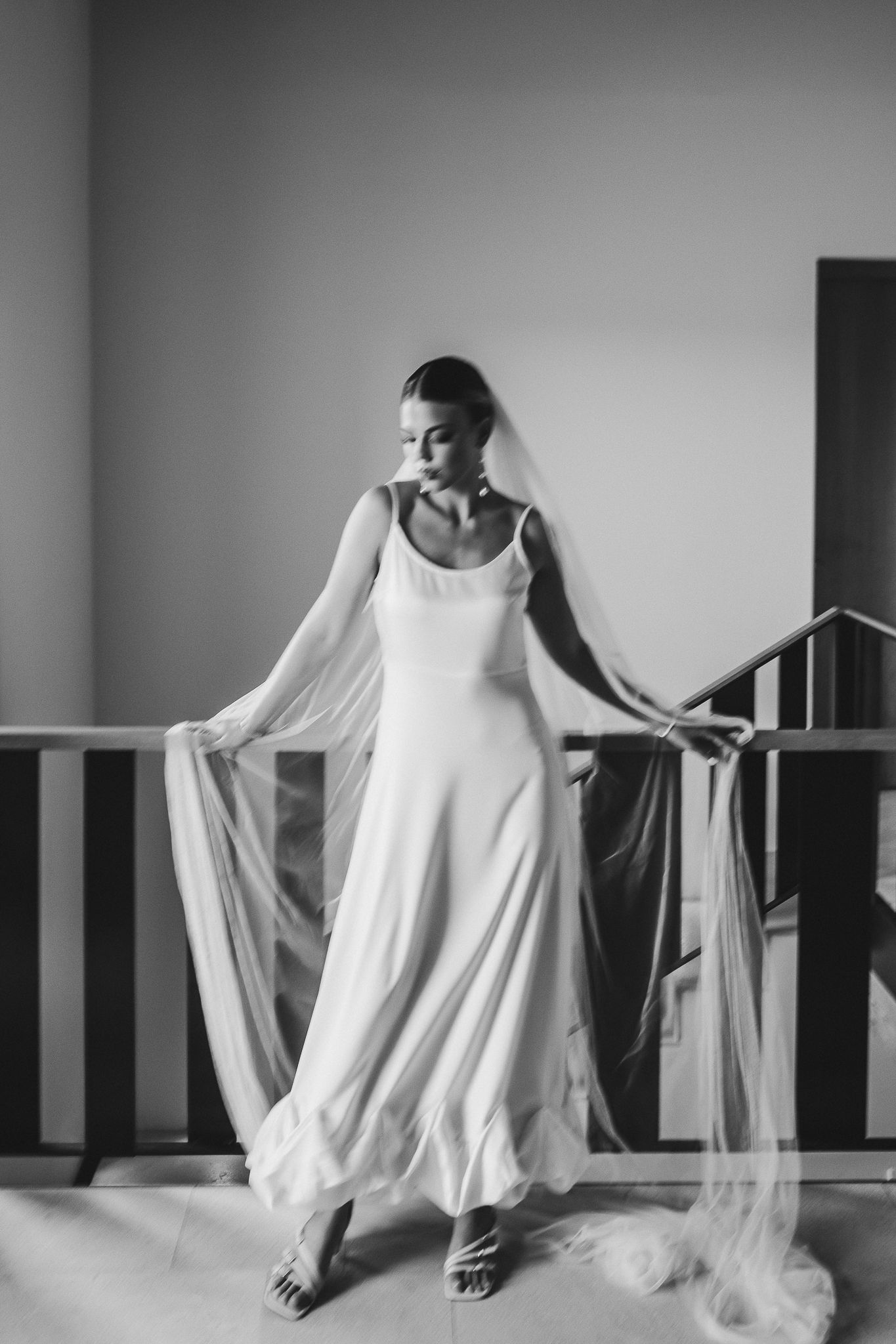 A sequence of black and white photos showing a dancer in flowing white fabric moving gracefully against a minimalist background.