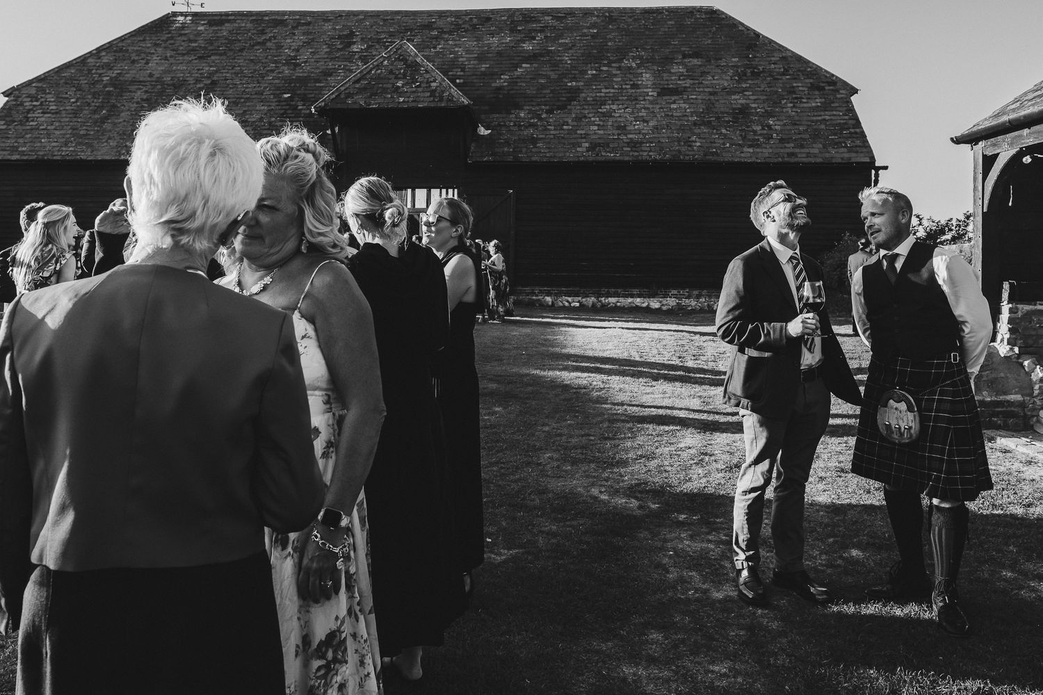 A series of black and white wedding photos showing outdoor ceremony moments and guest interactions.