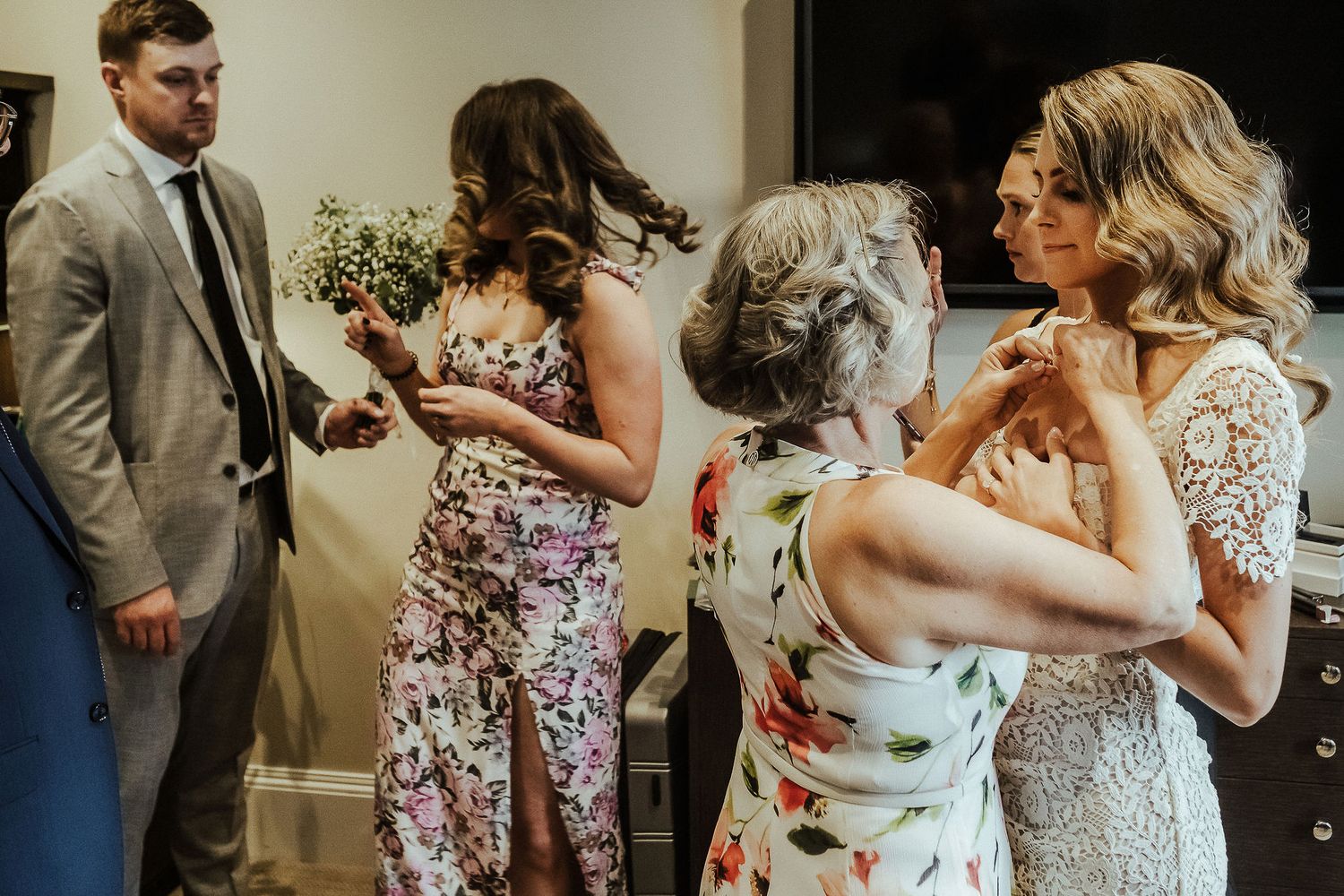 A group of wedding guests share a celebratory toast with champagne flutes in an elegant indoor setting.