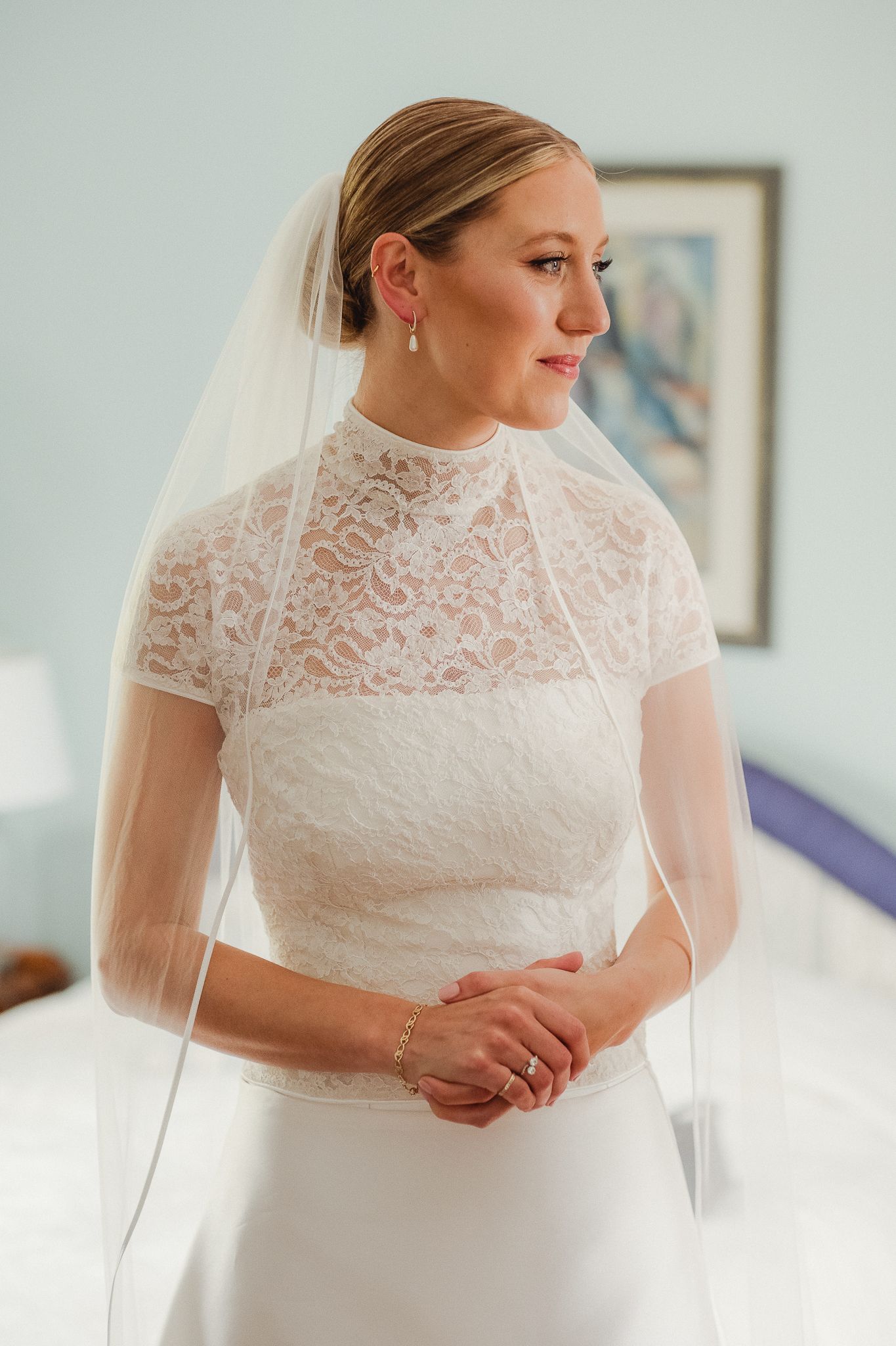 Beautiful bridal portrait showing lace wedding dress details and delicate veil in natural window light.